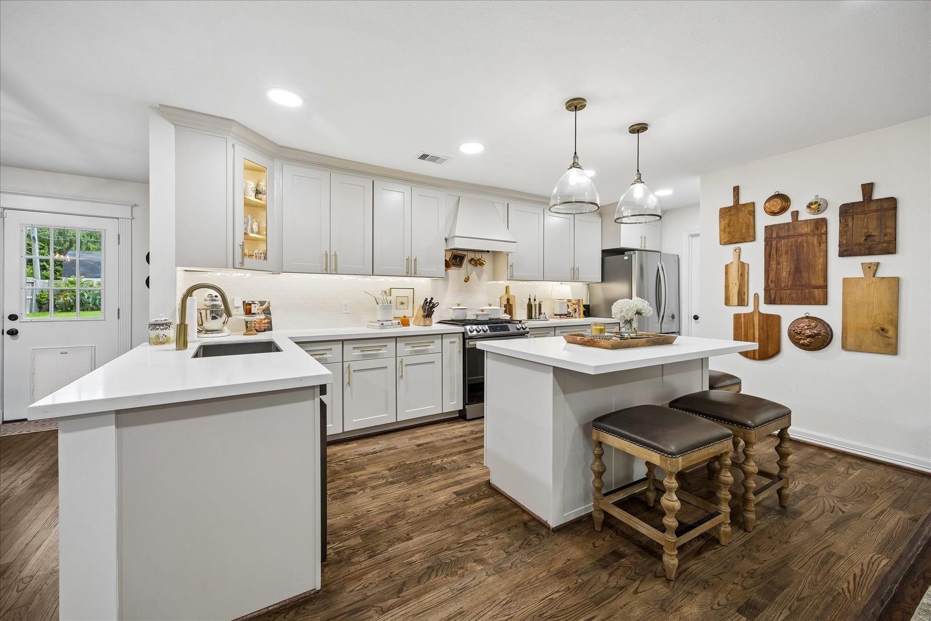 Modern kitchen with sleek white cabinetry, stainless steel appliances, and a central island with bar seating.