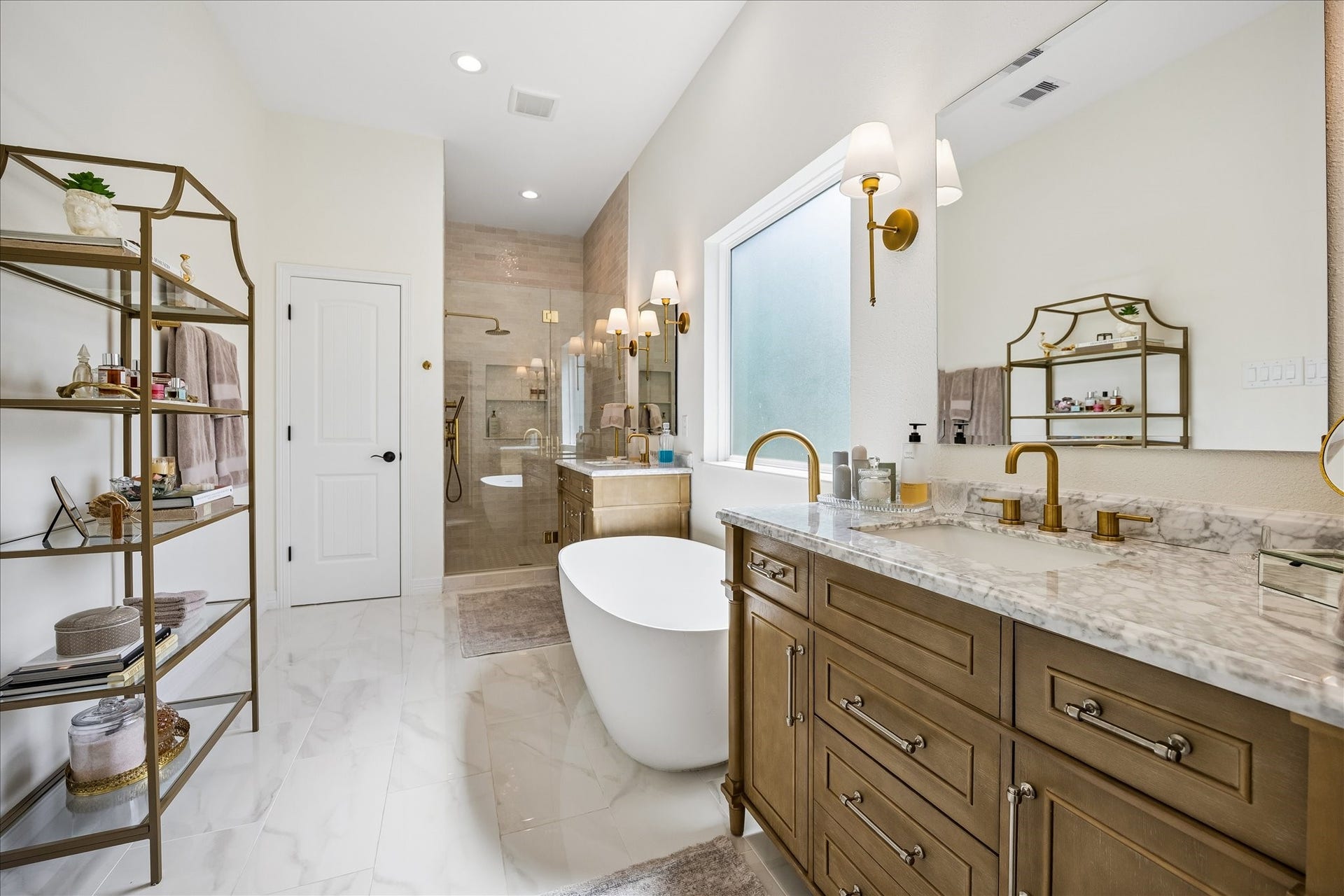 Luxurious bathroom featuring a freestanding soaking tub, large separate glass enclosed shower, & dual vanities with quartz tops & undermount sinks