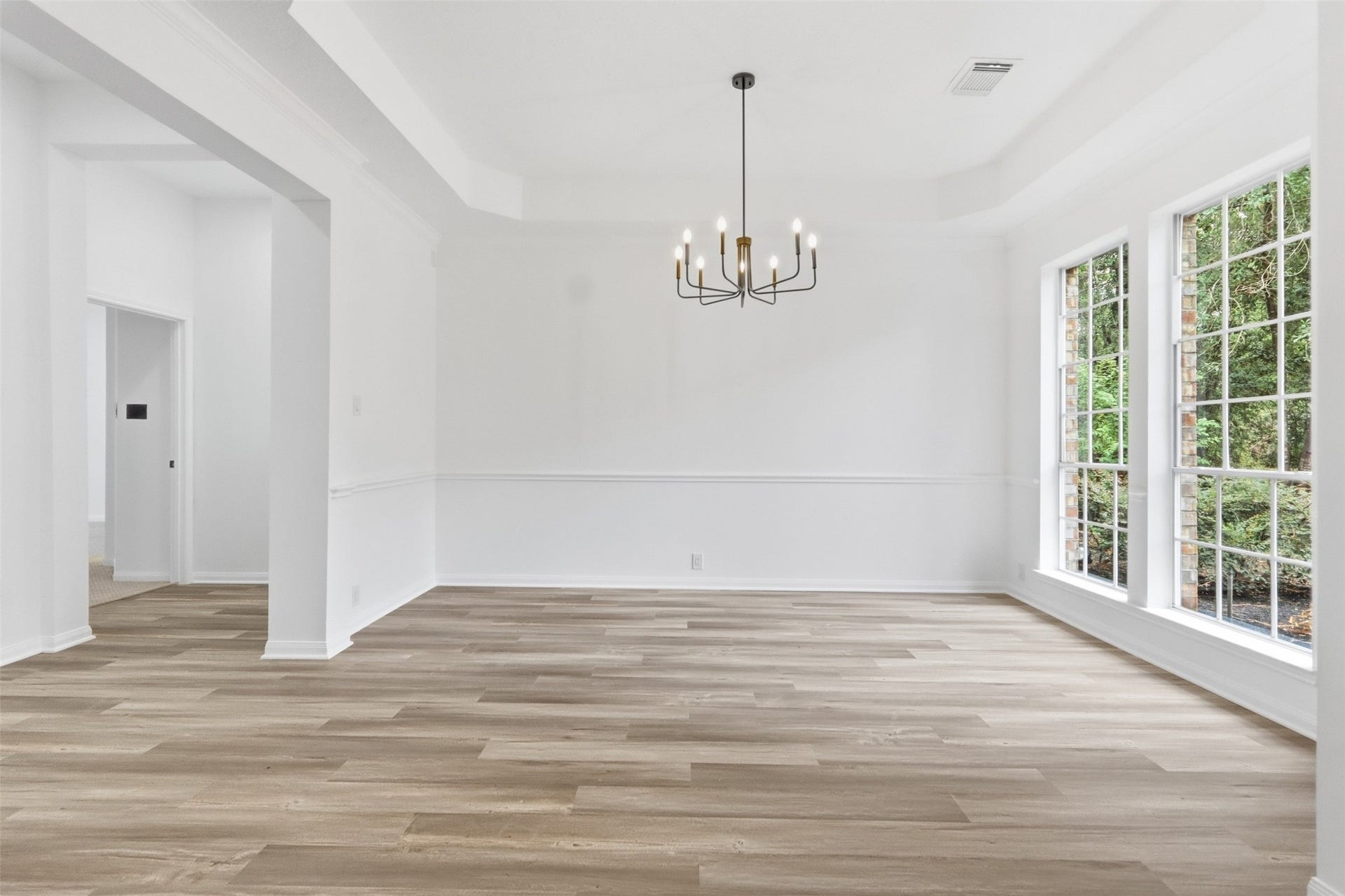 Formal dining room overlooks the front of the home and features a tray ceiling, accented by a contemporary chandelier that adds an elegant touch.