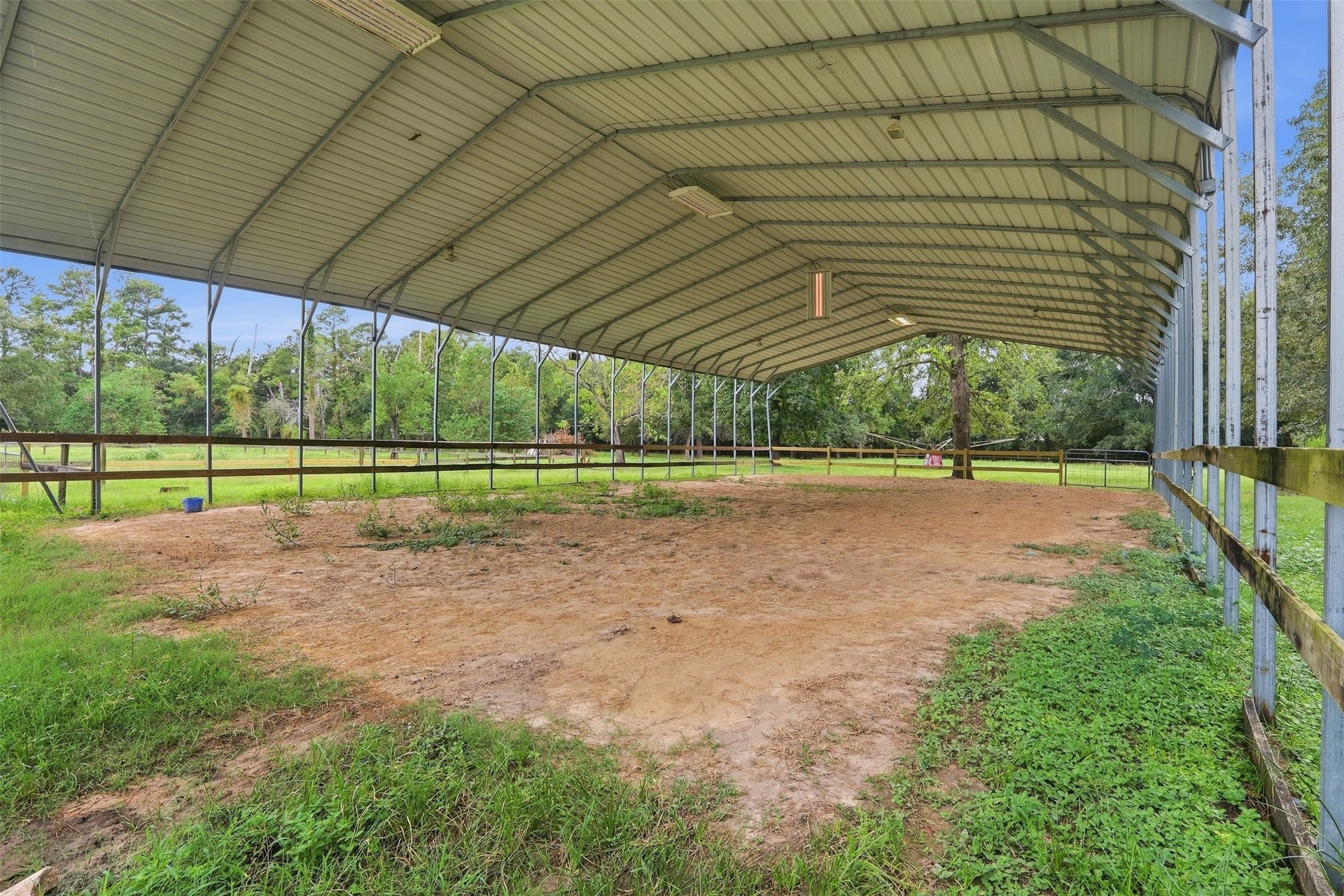 Covered riding area offers a wide, open space with a sturdy metal roof & fenced perimeter.