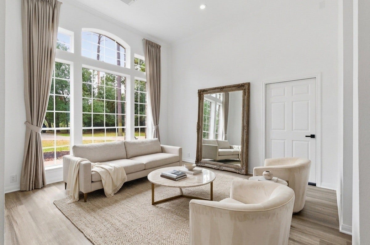 Formal living room overlooks the front of the home, featuring large windows that pour in natural light and an entry door leading to the garage. -VIRTUALLY STAGED-