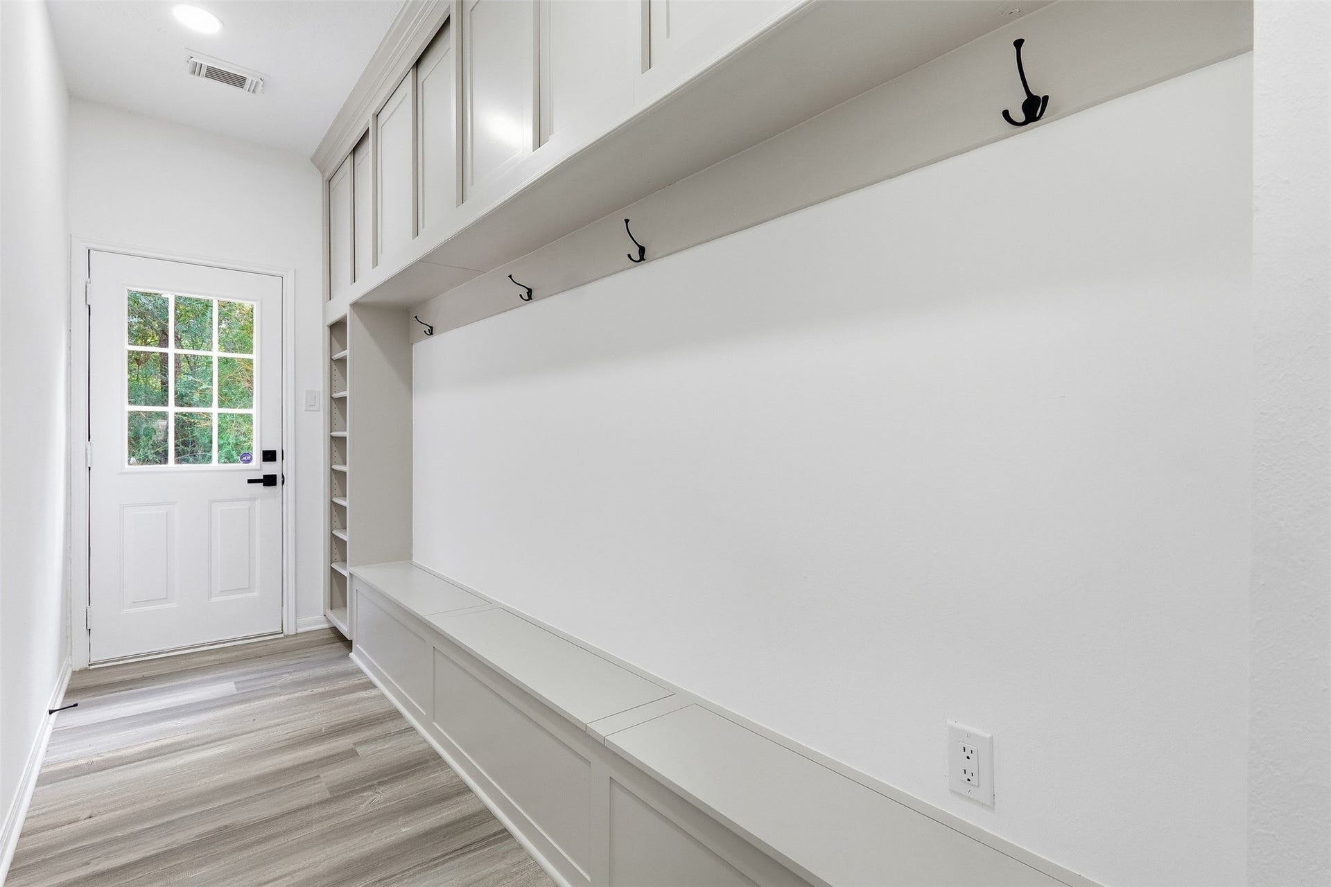 Mud room offers a built in bench with storage, upper cabinetry, a dedicated shoe shelf and hooks for coats and backpacks.