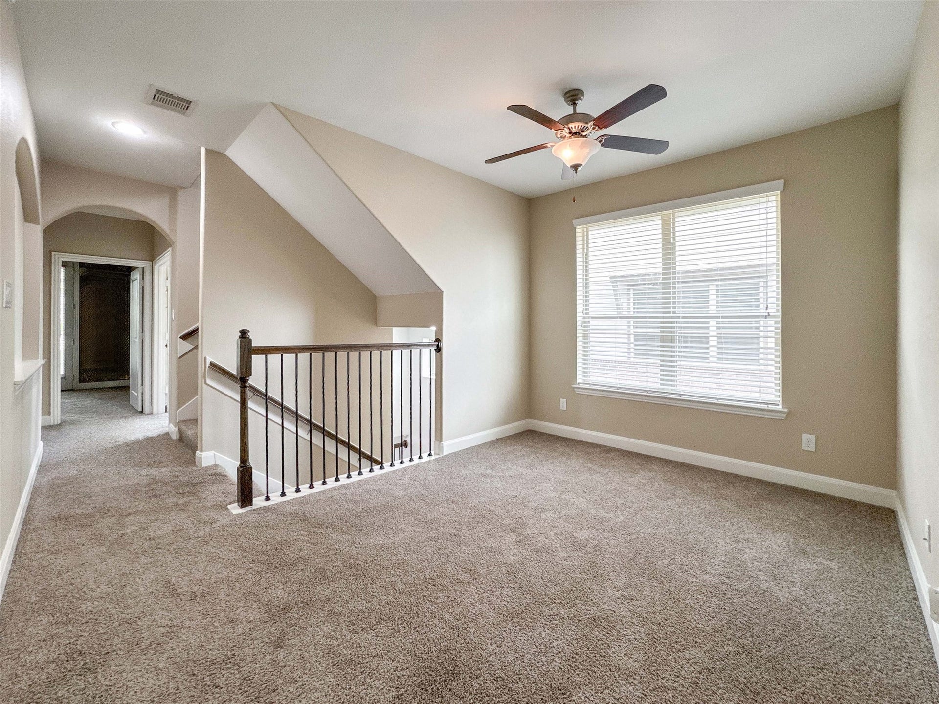Alternate view of the second floor gameroom with carpeted flooring, a ceiling fan, and a large window for natural light.