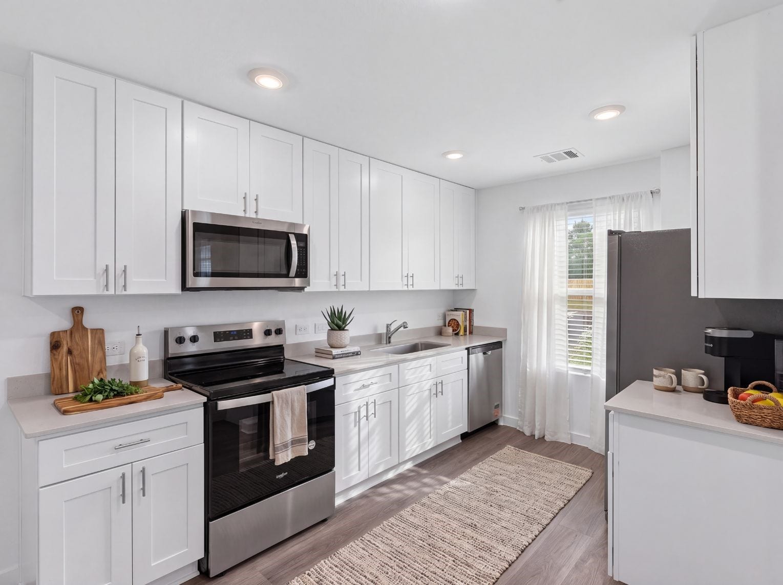 10816 N Baron Village Drive, Conroe, TX 77306 Full view of the kitchen showing ample white cabinetry, stainless steel appliances, light counters, and a window above the sink. Wood-look flooring and a walk-through layout add function.
This photo has been digitally staged to illustrate the possibilities of the home's aesthetic and potential design. Some furnishings and dcor shown are for visual inspiration.
