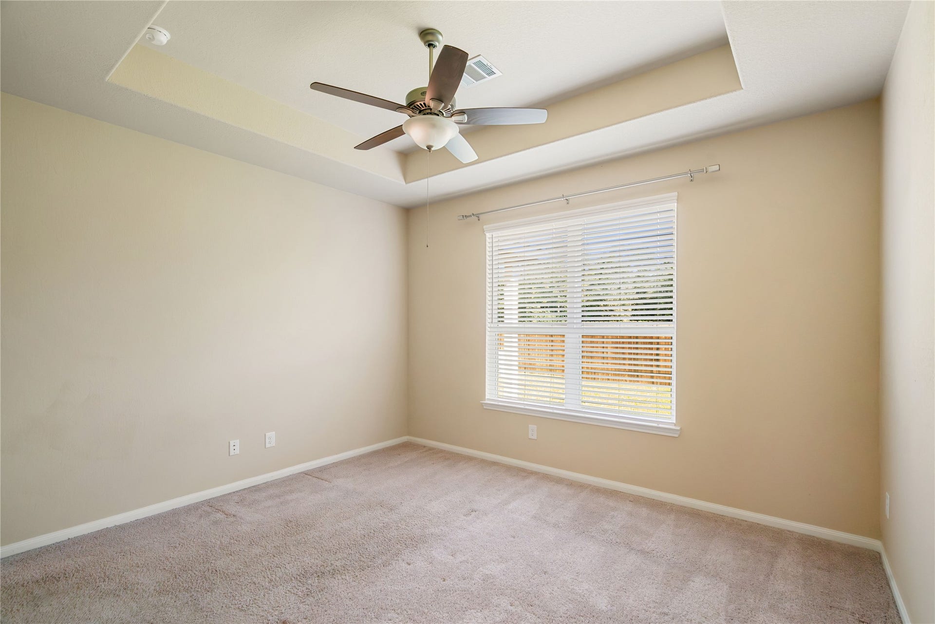 Primary bedroom offers a blank canvas with its neutral color, natural light and wooded backdrop view.
