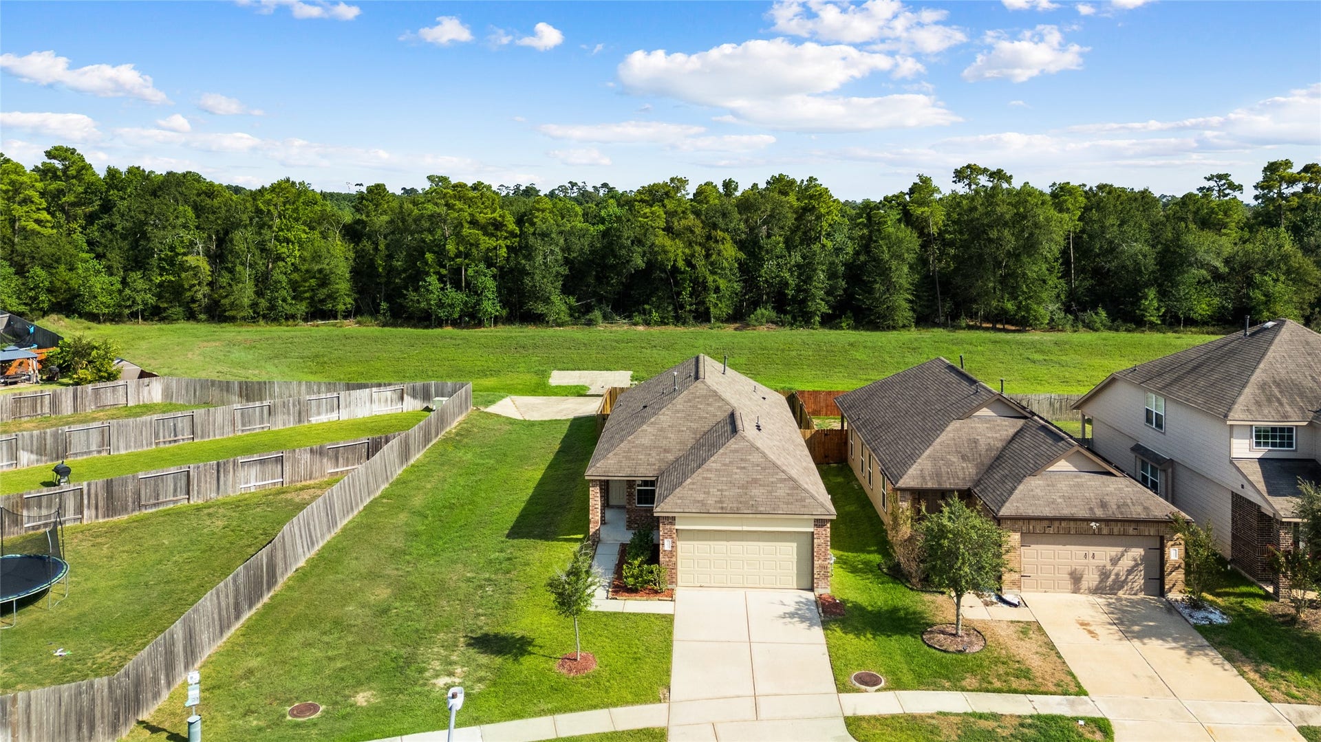 Aerial view highlights this home's unique setting with expansive green space along the side and no back neighbors. A beautiful lush backdrop provides added privacy and a more open feel rarely found in a neighborhood setting.