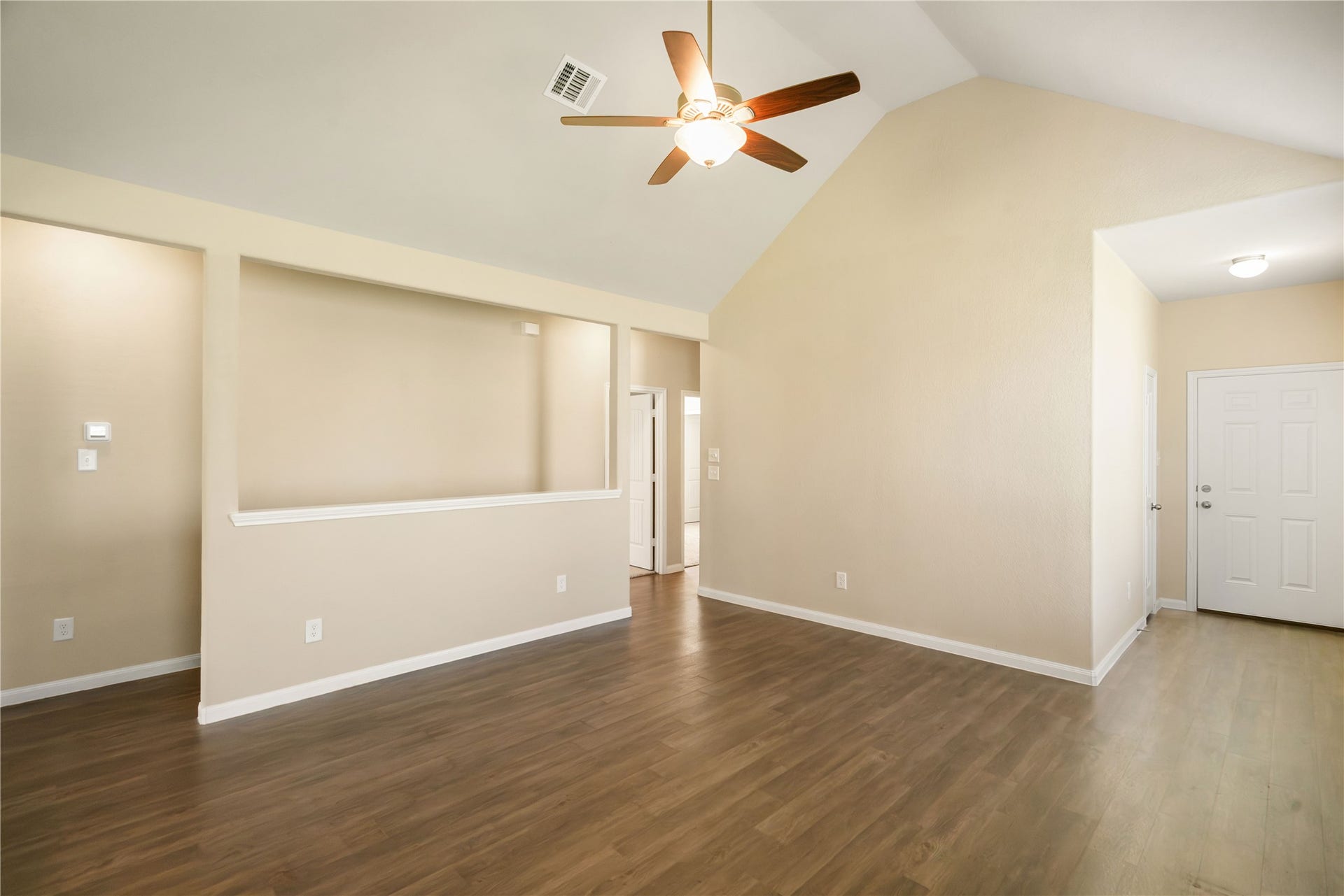 Spacious living area featuring vaulted ceilings opens to the kitchen/dining area and beautiful flooring creates a bright, open feel with plenty of flexibility for furniture placement.