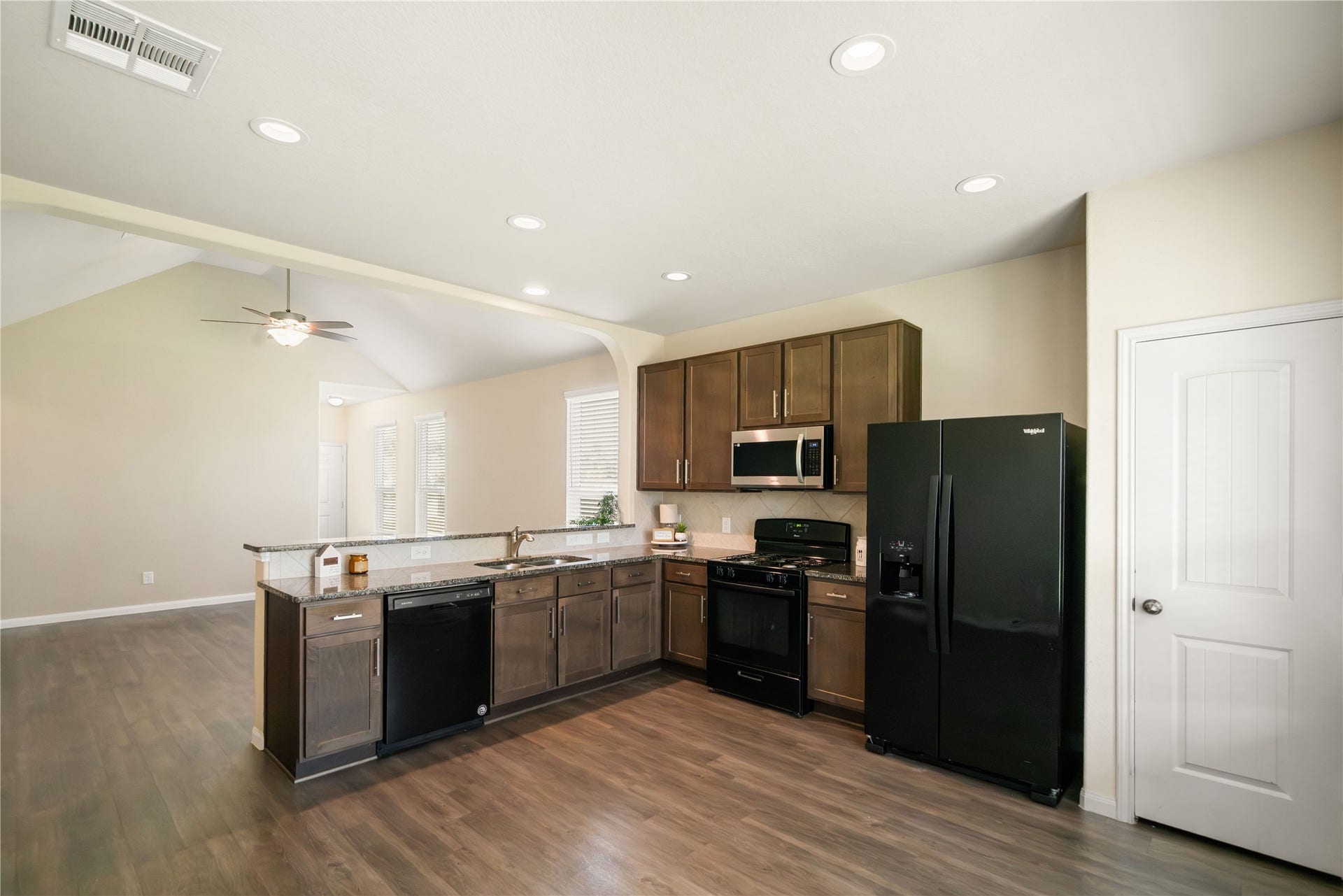 Functional, open kitchen featuring granite countertops, rich cabinetry, recessed lighting, pantry, and a breakfast bar overlooking the living areaa layout designed to keep everyone connected.