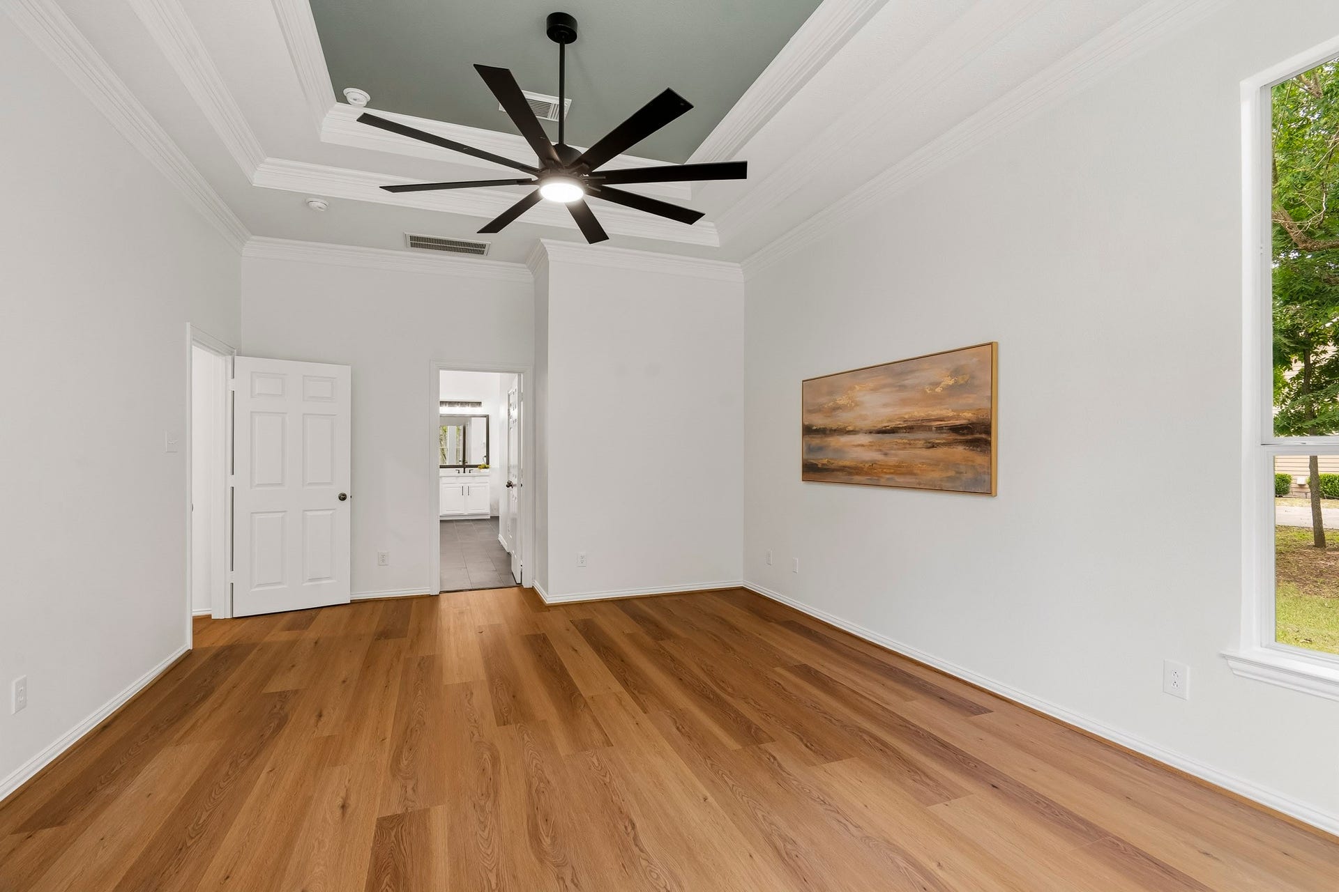5202 Bessies Creek Trace, Fulshear, TX 77441 The Primary Bedroom showcases new LVP flooring, a sophisticated double tray ceiling, exquisite crown molding, and a stylish new five-blade ceiling fan. Bathed in natural light, the rooms fresh, bright palette creates an inviting and versatile retreat, providing the perfect canvas for any design style while enhancing the sense of comfort, elegance, and spaciousness.