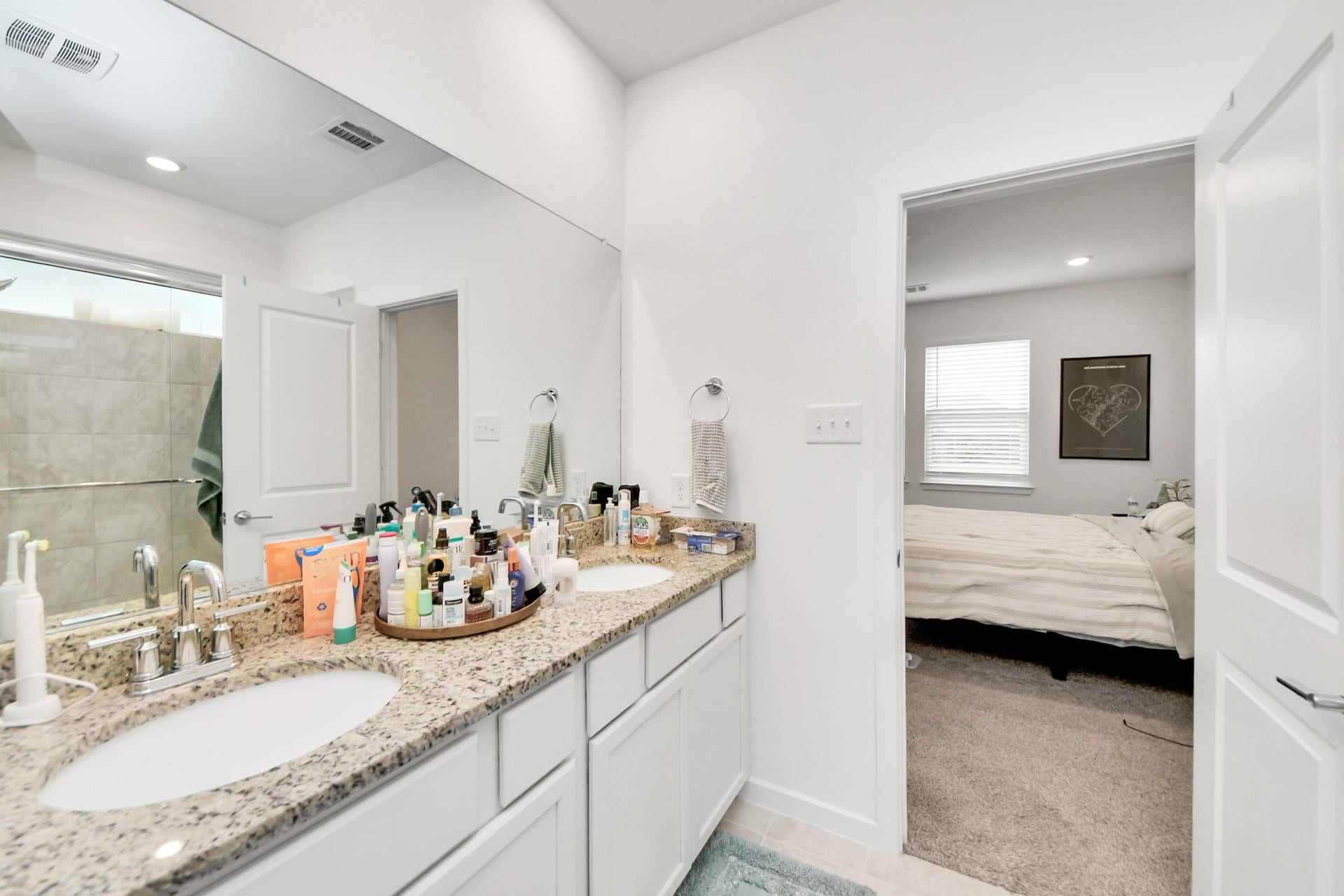 Dual vanities in the primary bathroom with granite countertops.