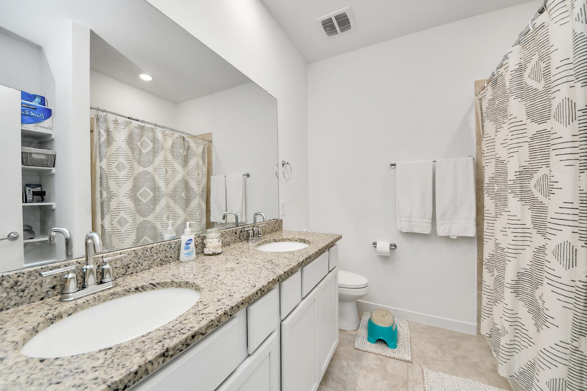 Secondary bathroom with double vanities and granite countertop.