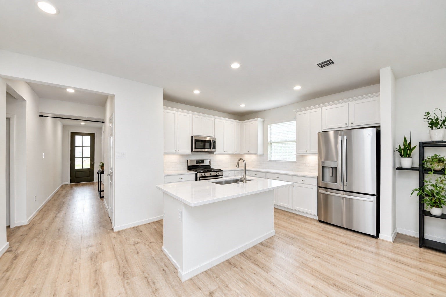 Bright open kitchen with subway tile and tall  trimmed cabinets.