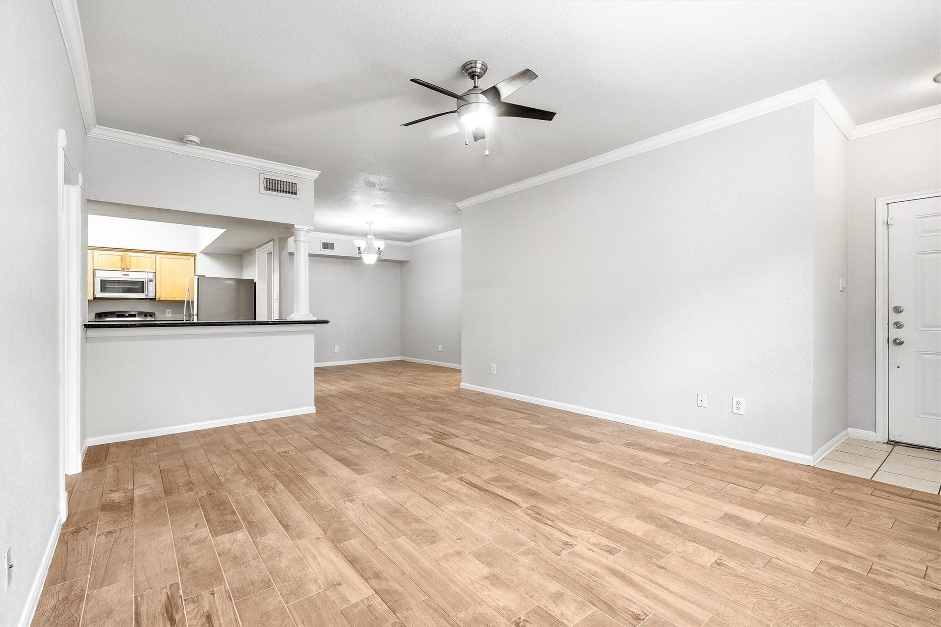 Bright and versatile living area with ceiling fan, crown molding, and an easy-flow layout.