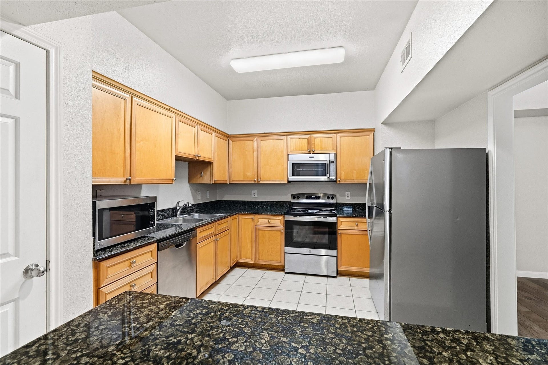 Granite breakfast bar creates a natural connection between the kitchen and living space, ideal for casual dining or entertaining.