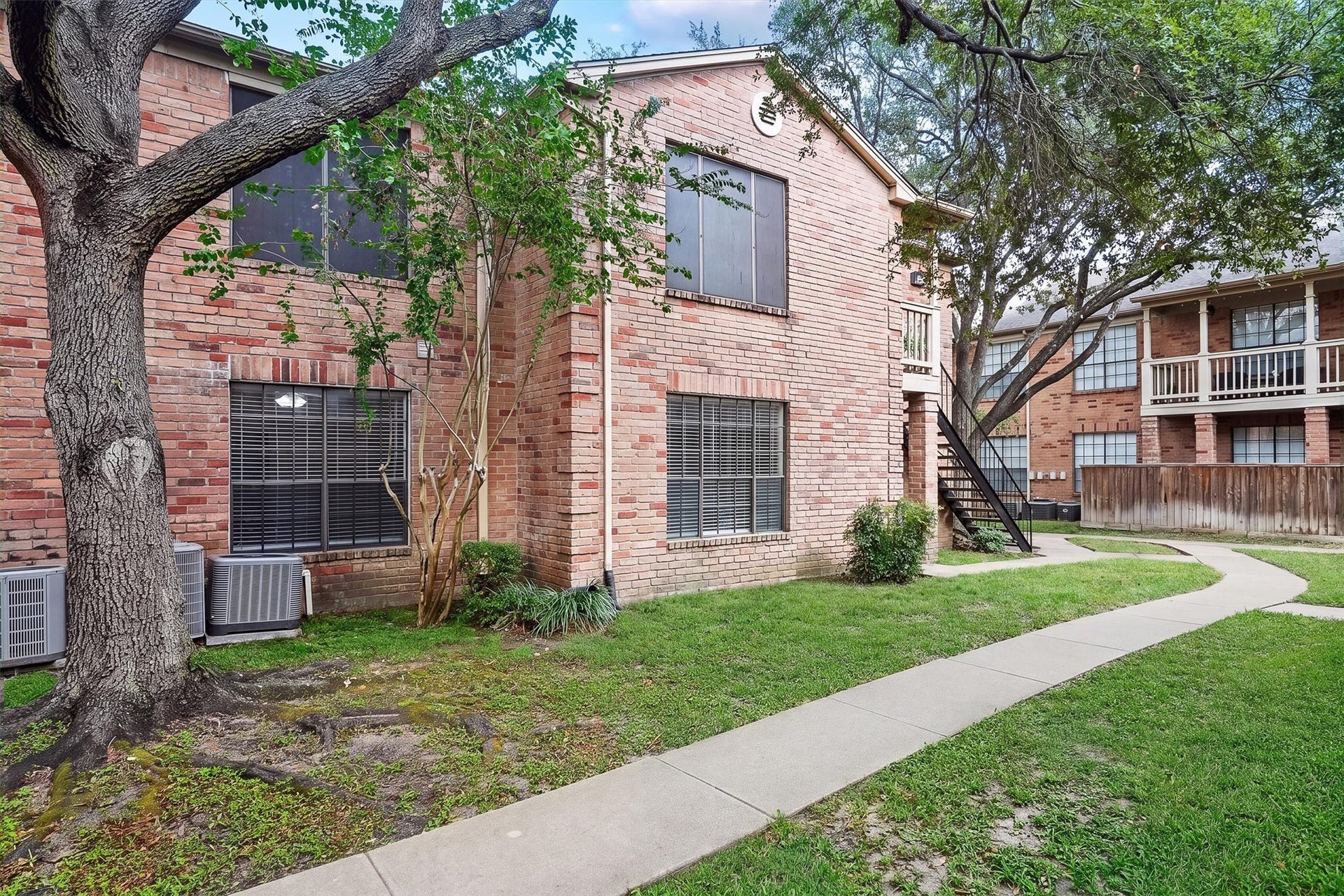 Rear and side view of the building with mature shade trees and convenient pedestrian walkways.