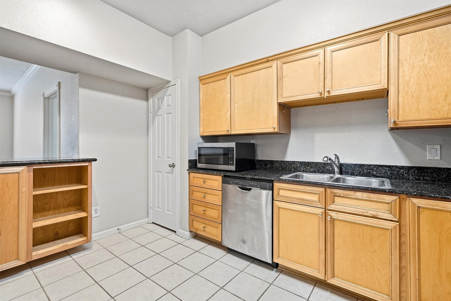 Kitchen offers plenty of storage, stainless steel refrigerator, tile flooring, and convenient access to the living area.