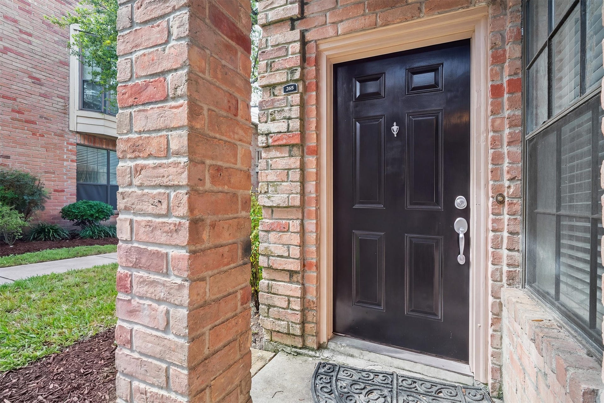 Covered private entrance framed by brick detailing and a classic paneled front door.