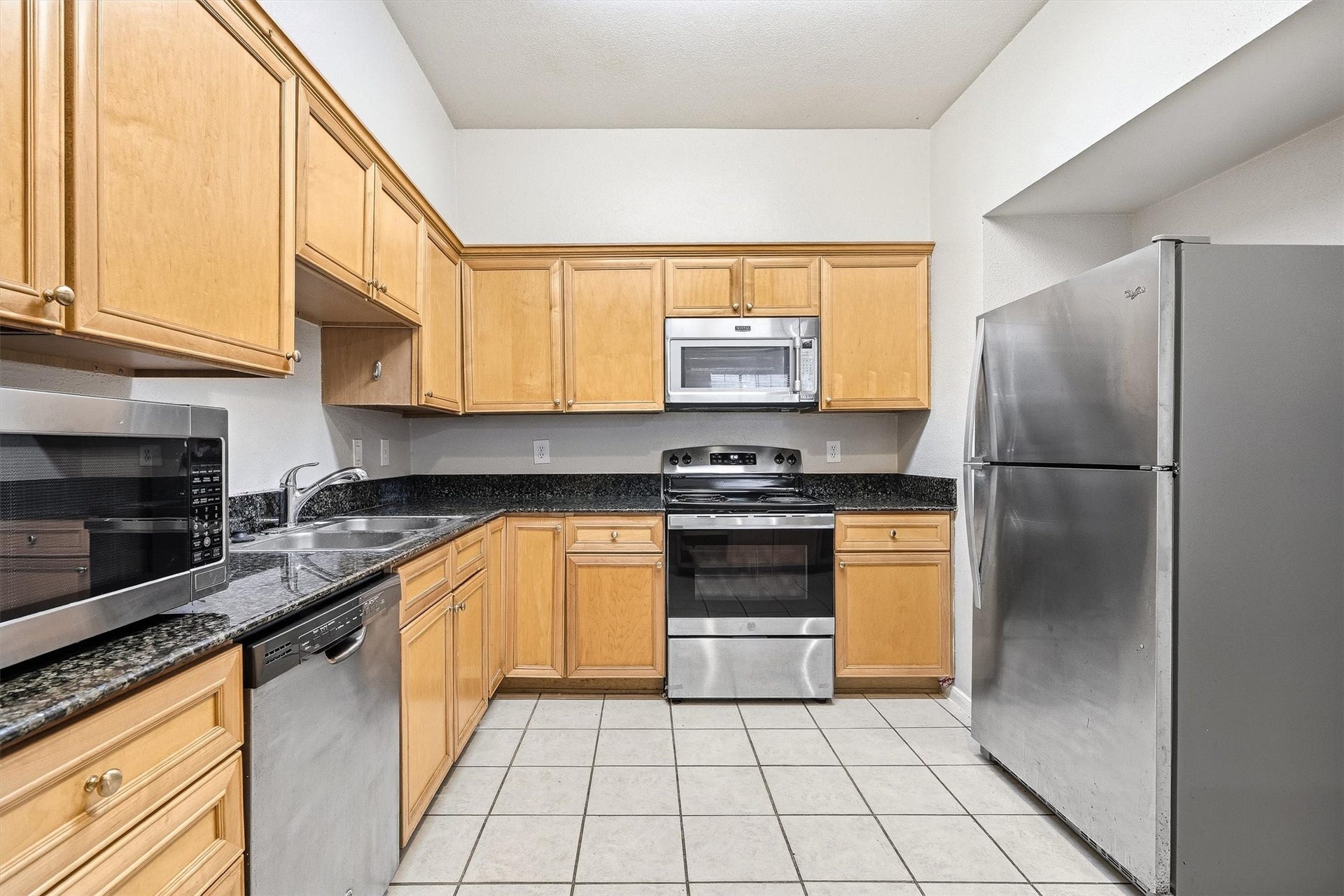 Additional kitchen view highlighting generous cabinet storage, granite countertops, and stainless steel appliances.