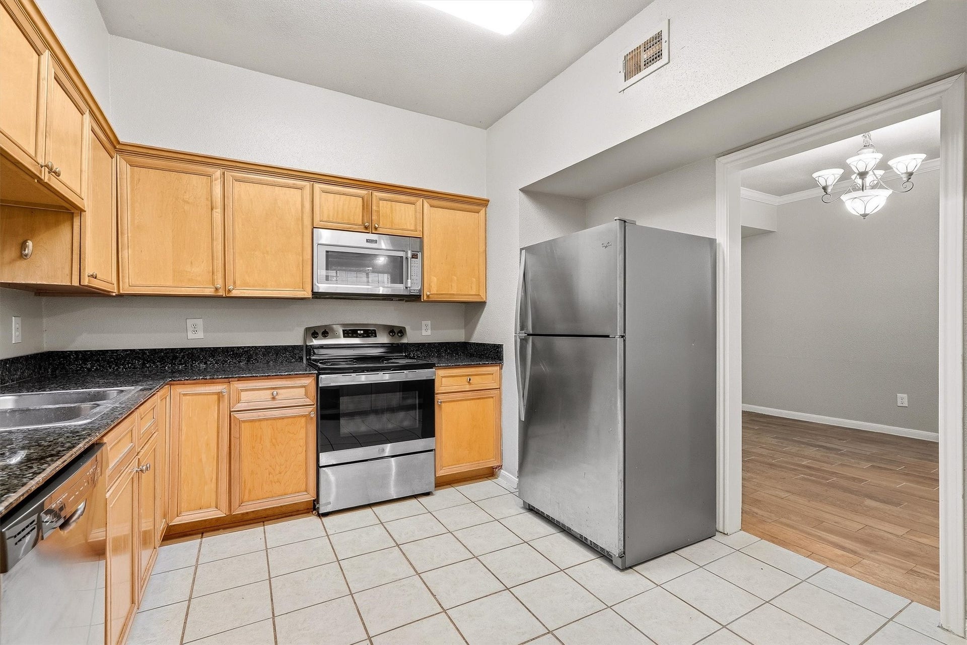 Functional kitchen with abundant cabinetry, granite countertops, stainless steel dishwasher, and double-basin sink.