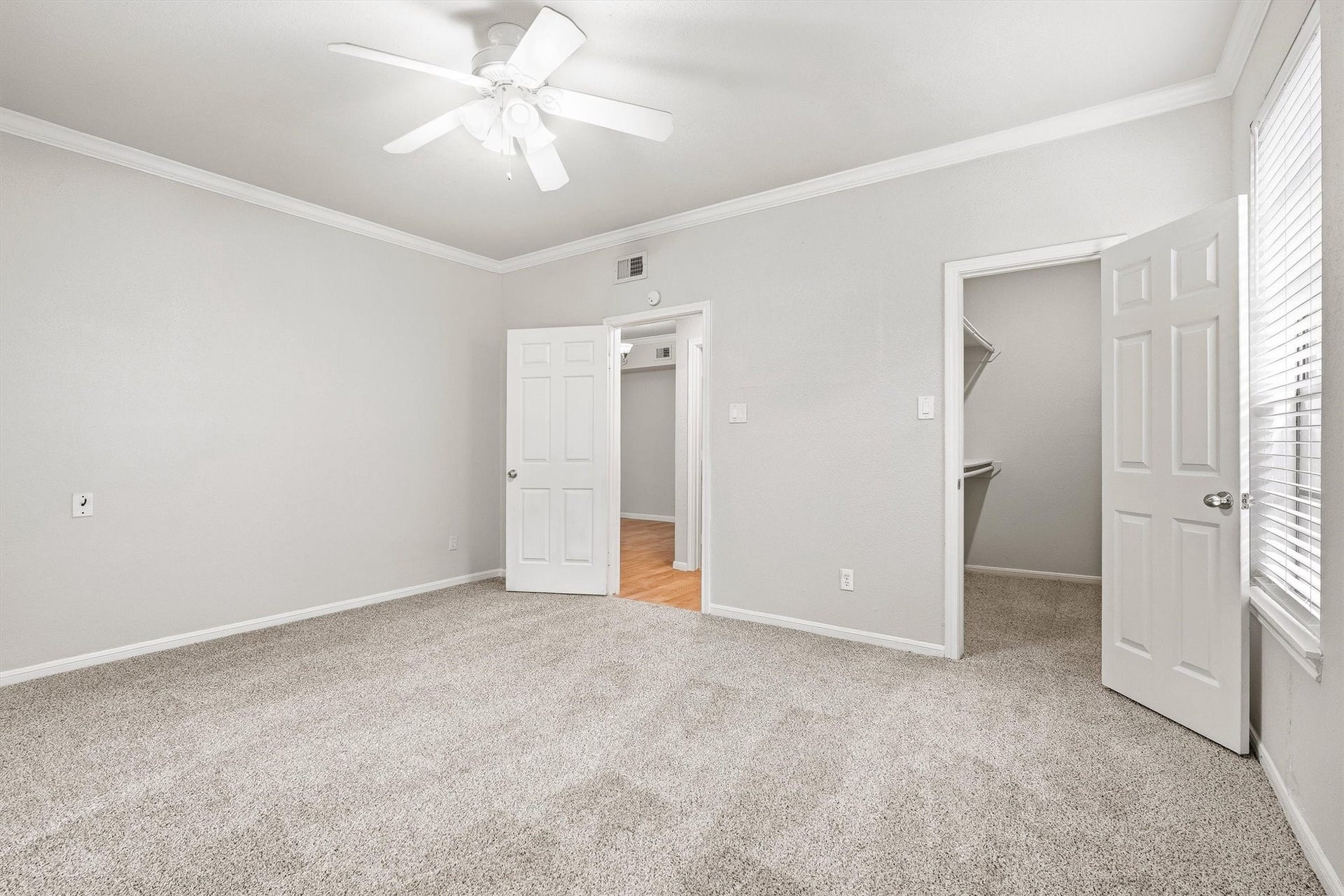 Alternate view of the primary bedroom highlighting generous proportions, neutral finishes, and convenient closet access.