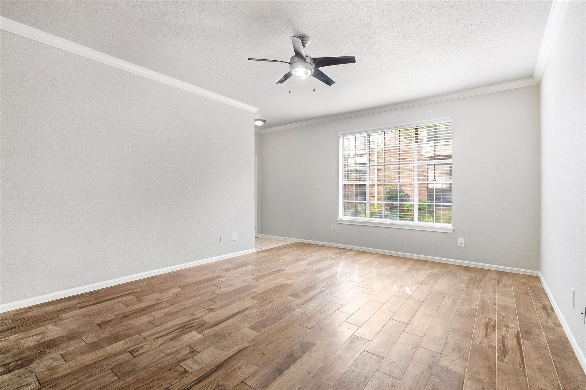 arge window brings natural light into the living space, complemented by wood-look flooring and neutral tones.