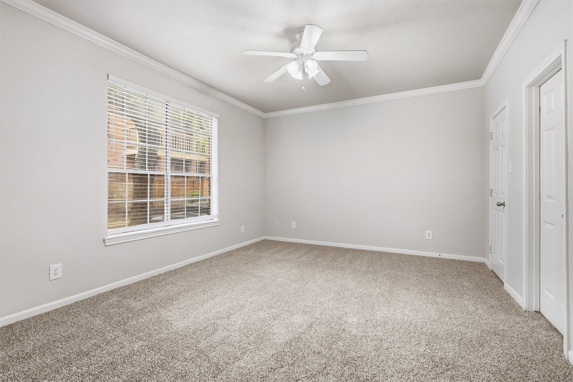 Well-sized secondary bedroom with carpet, crown molding, ceiling fan, and a large window for natural light.
