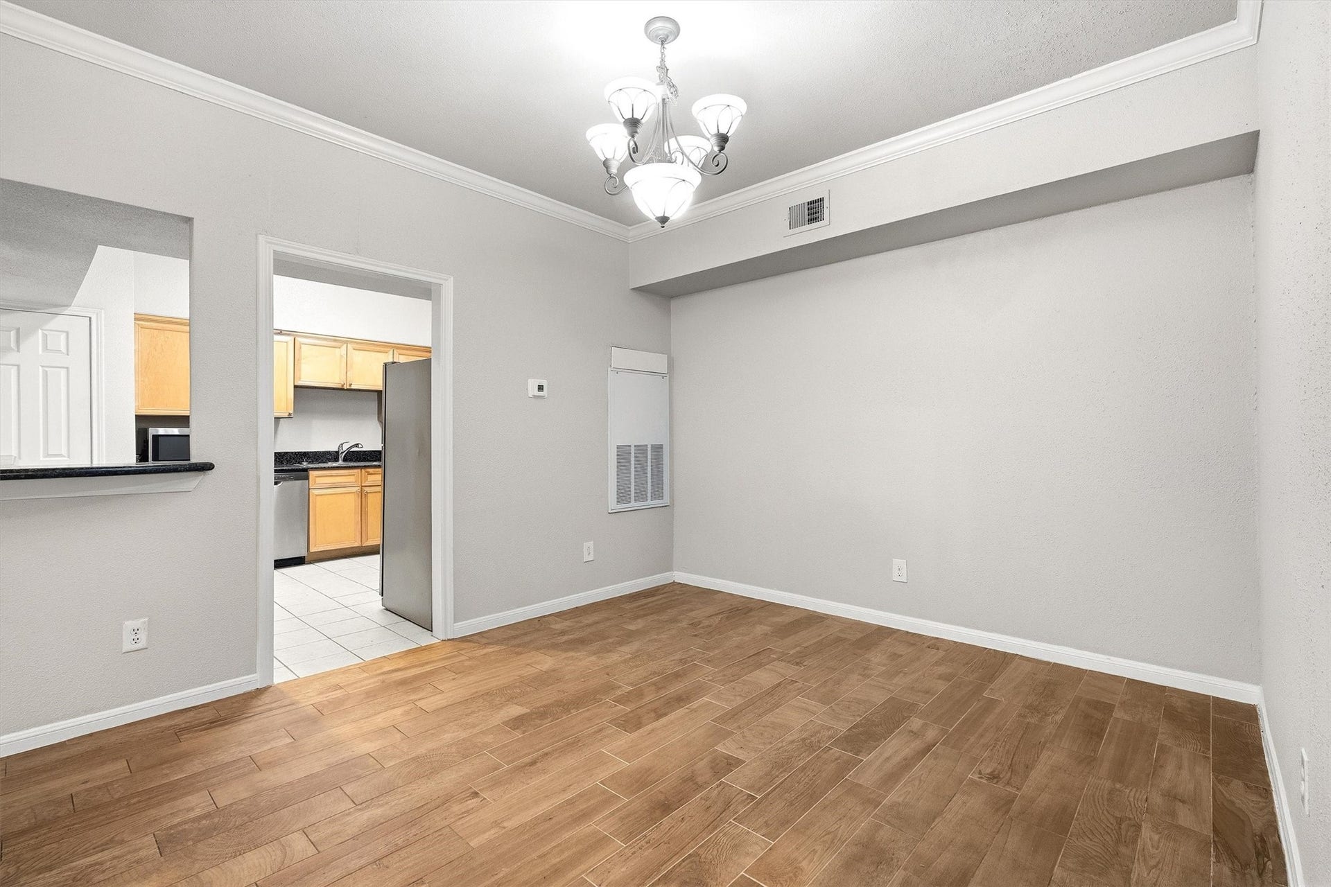 Additional dining room view showcasing the chandelier, crown molding, and open layout.