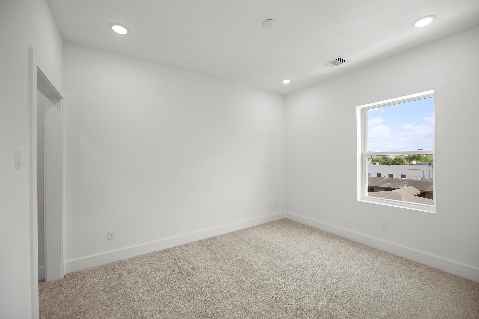 870 W Little York Road, #A, Houston, TX 77091 This secondary bedroom on the third level is bright, carpeted, white walls, recessed lighting, and a window offering natural light and an outdoor view.