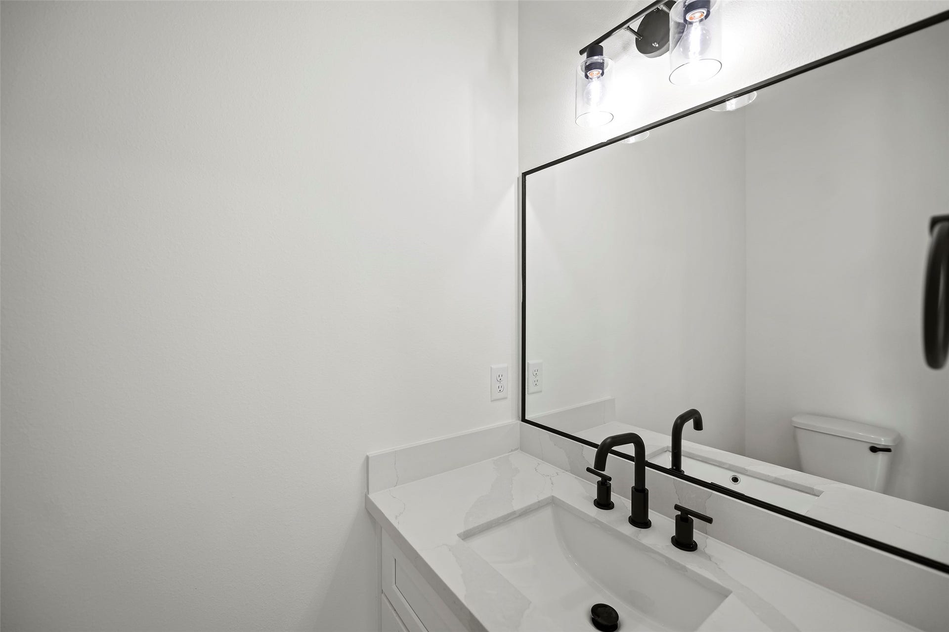 870 W Little York Road, #A, Houston, TX 77091 Modern half bathroom with a sleek white vanity, black fixtures, a large mirror, and bright lighting.