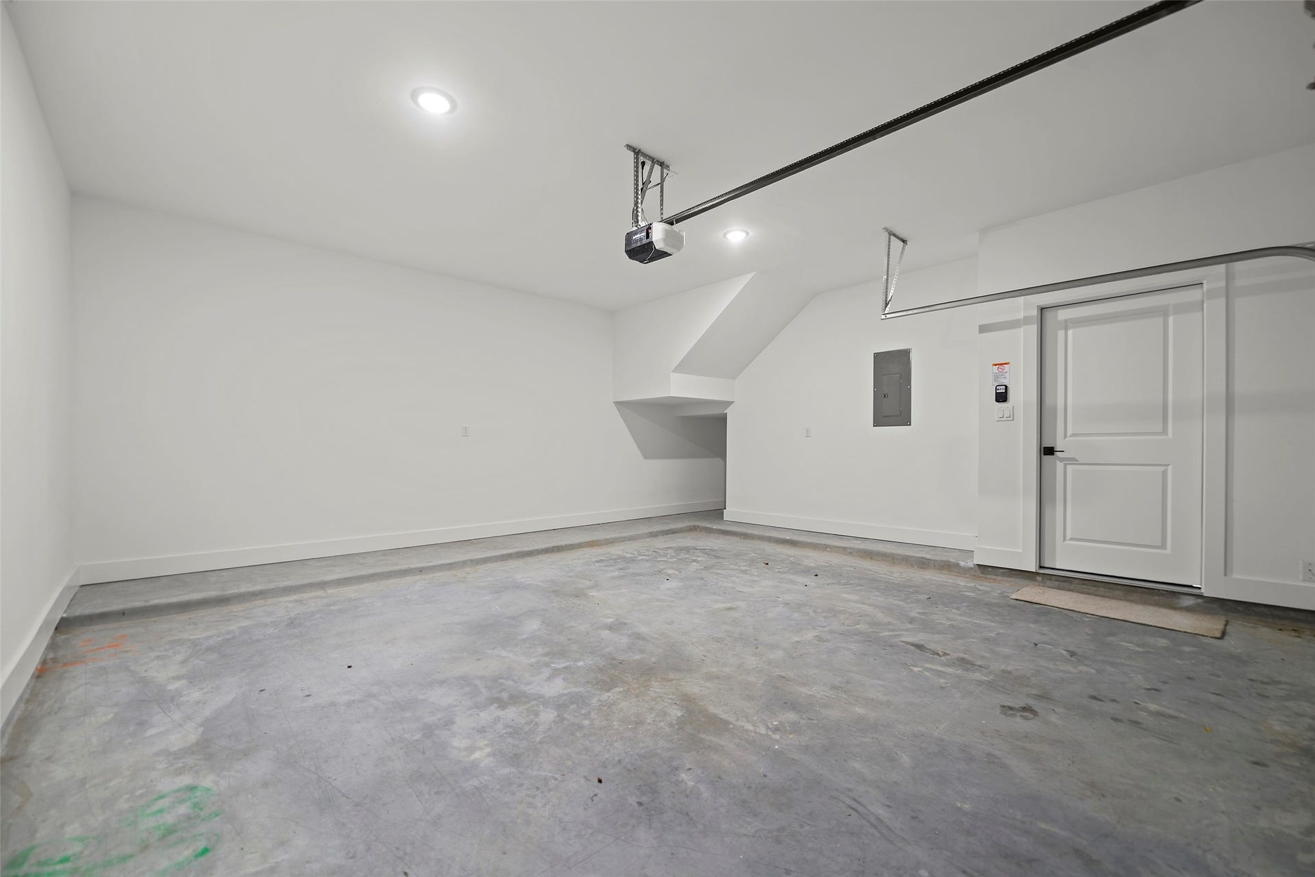 870 W Little York Road, #A, Houston, TX 77091 This photo shows a spacious, clean, and well-lit garage with concrete flooring, white walls, and a door leading inside. It features a garage door opener and ample space for parking or storage.