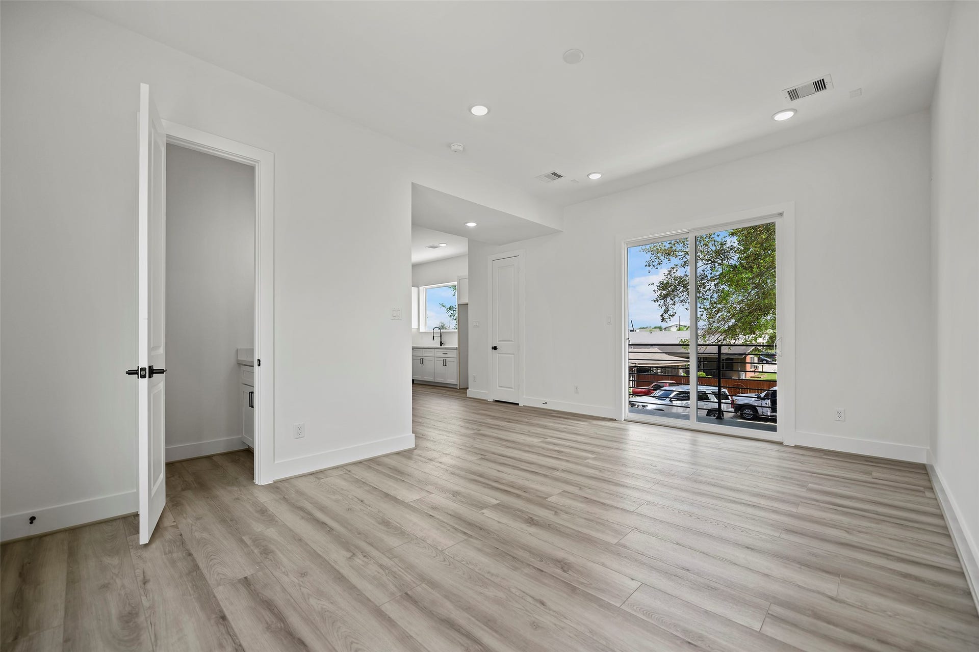 870 W Little York Road, #A, Houston, TX 77091 The living area showcases a bright and spacious room with modern LVP flooring, recessed lighting, and natural walls. It features an open layout with a staircase leading down, ideal for versatile use and customization.