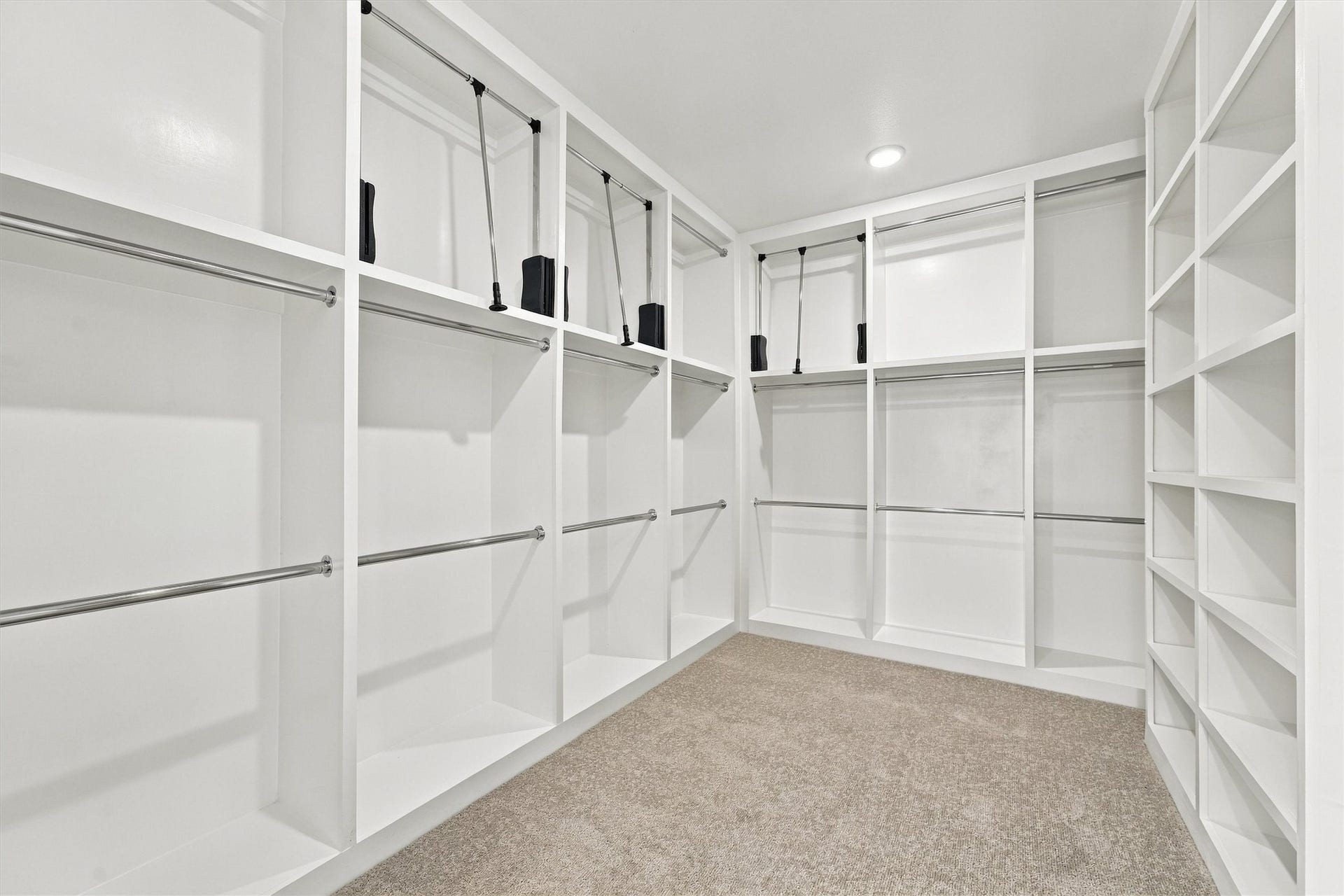 A boutique-style closet with floor-to-ceiling built-ins, double hanging, and pull-down rods.