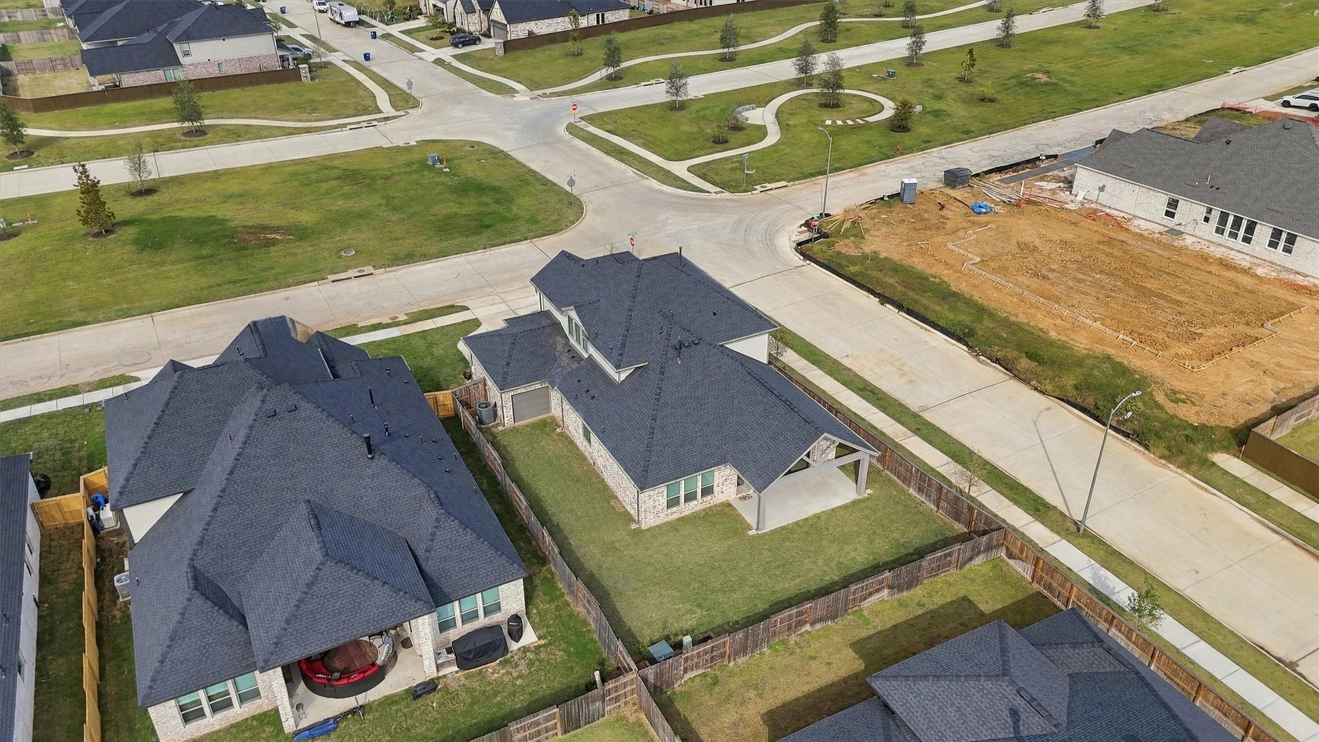 The covered patio, the drive-through garage bay, and the fenced side yard along the corner.