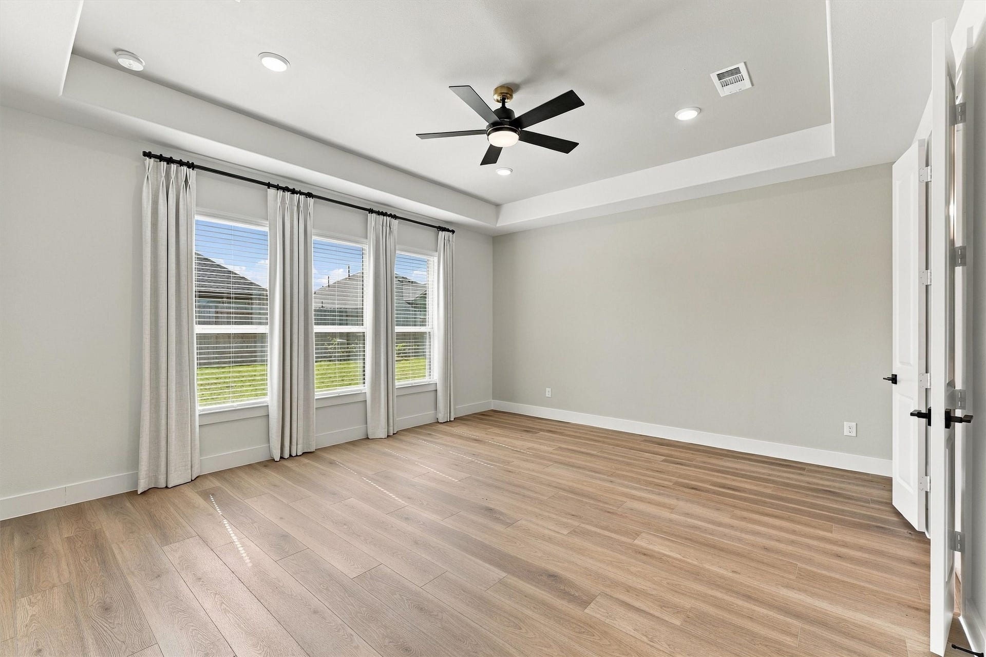 A tray ceiling, a wall of windows overlooking the backyard, and double-door entry create a serene retreat.