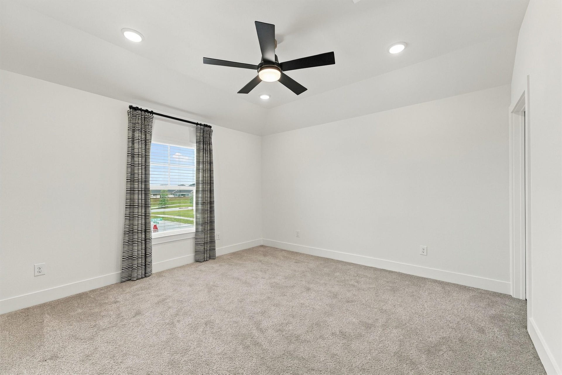 A spacious bedroom with a ceiling fan, recessed lighting, and plenty of natural light.