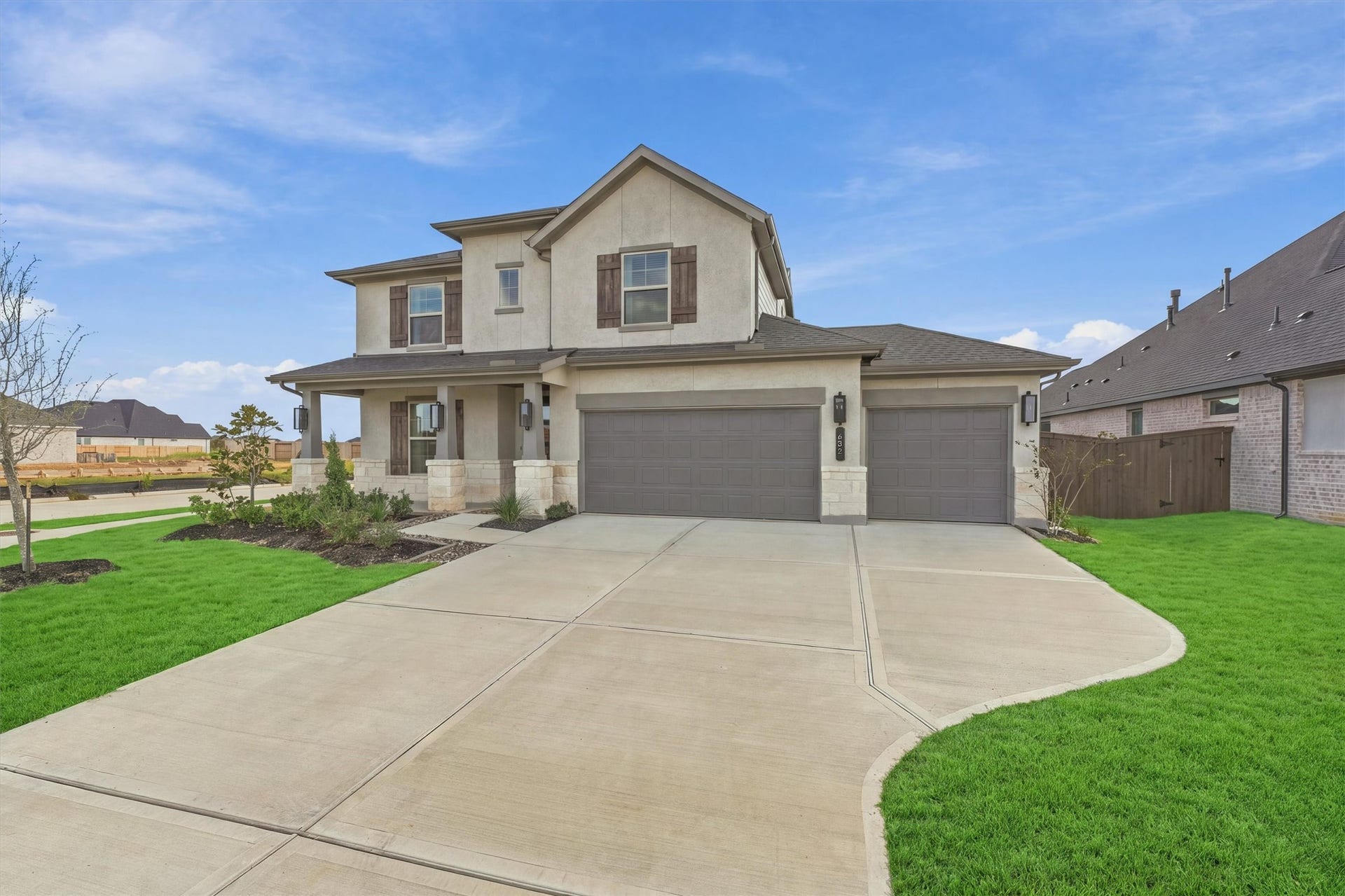 A sweeping driveway leads to the three-car garage, framed by manicured landscaping and a generous front lawn.