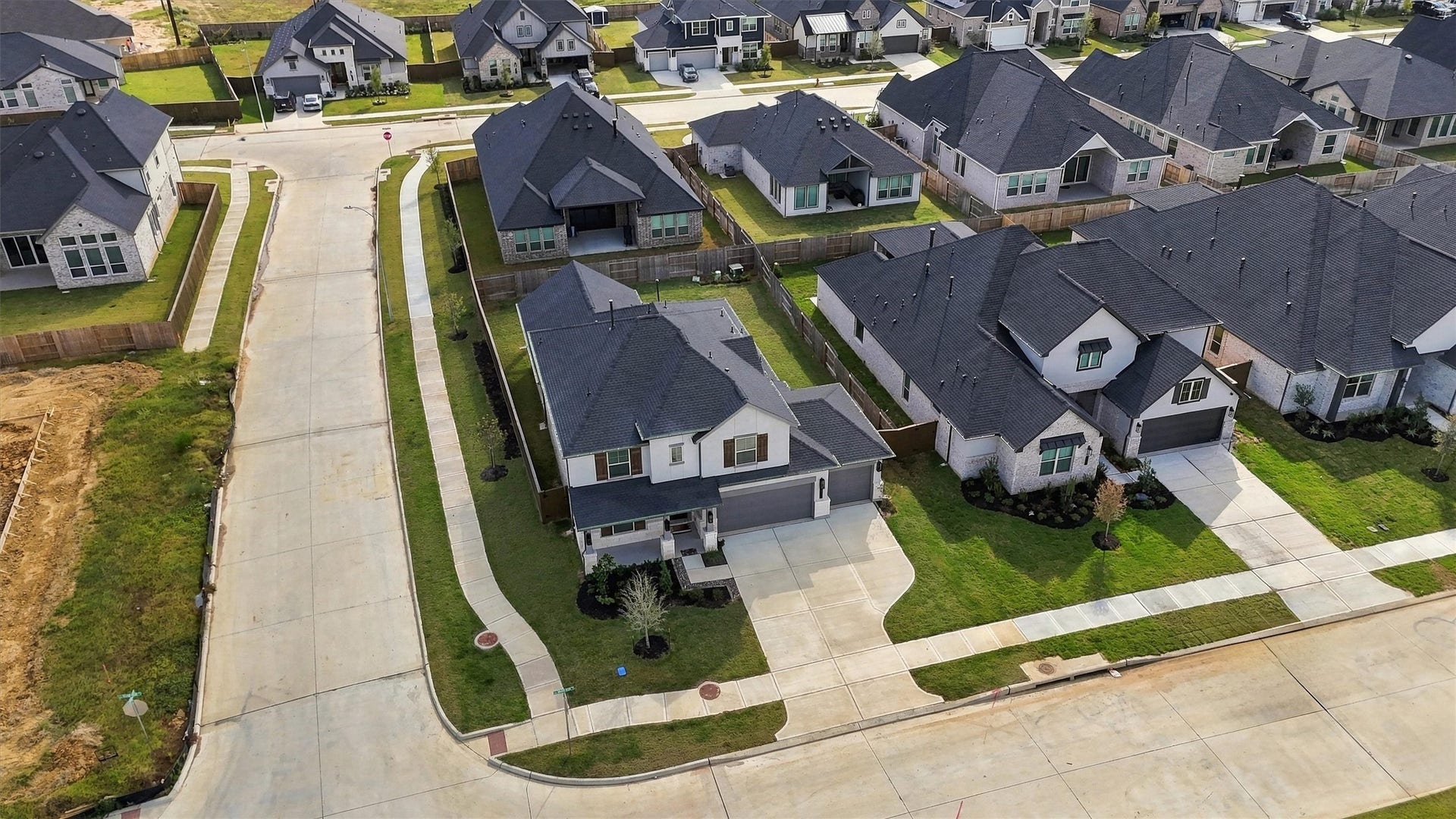 The corner placement, the landscaped front yard, and the three-car garage.