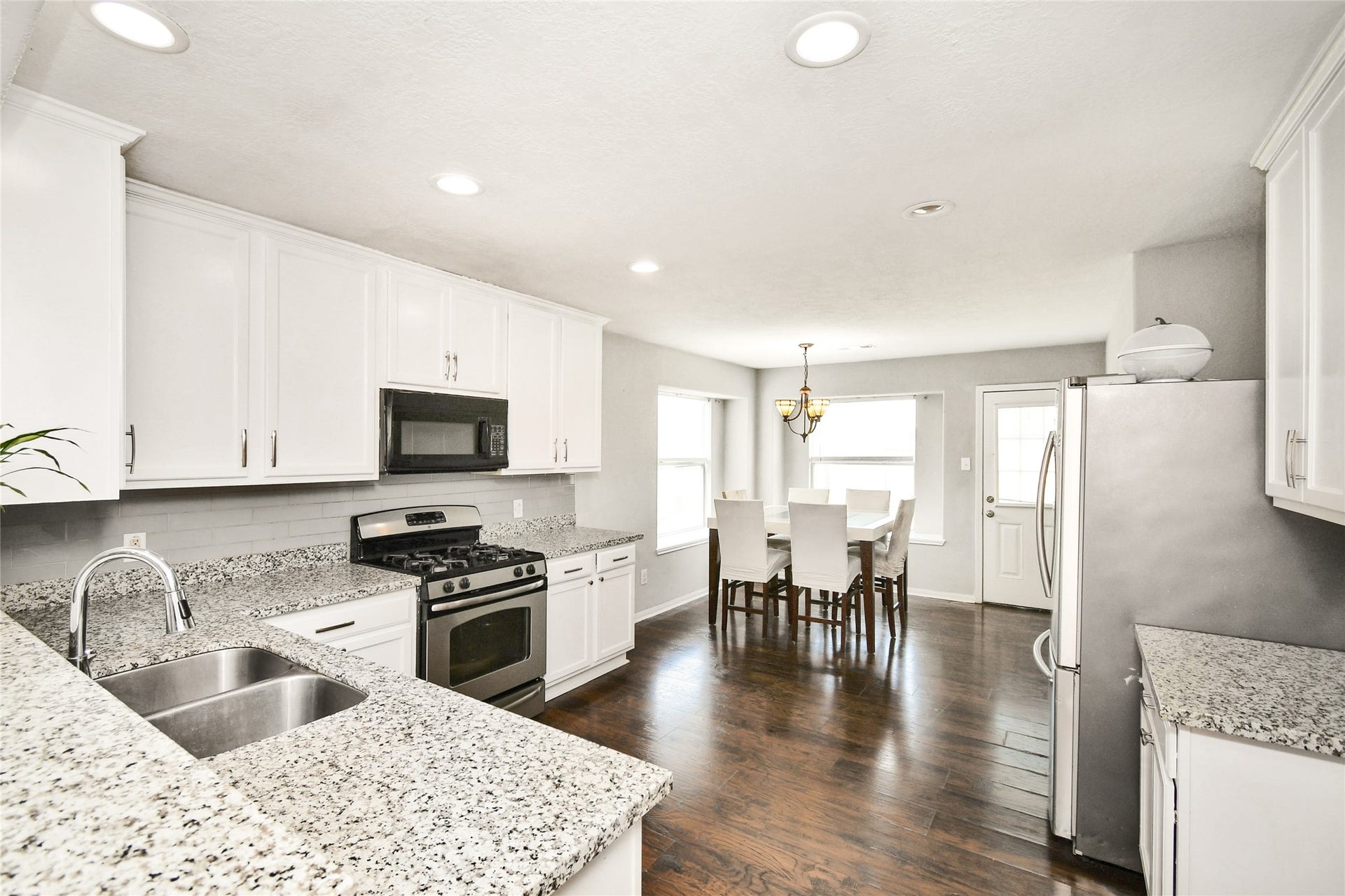 2319 Blue Reef Drive, Katy, TX 77449 Beautifully updated kitchen with white cabinetry, granite countertops, and stainless steel appliances, opening to the dining area.