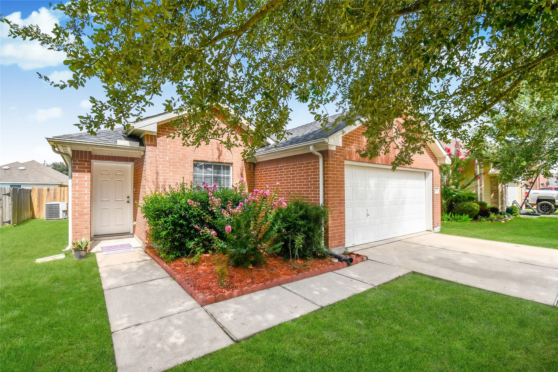 2319 Blue Reef Drive, Katy, TX 77449 Beautiful curb appeal featuring a mature shade tree, blooming crape myrtles, and a well maintained brick exterior.