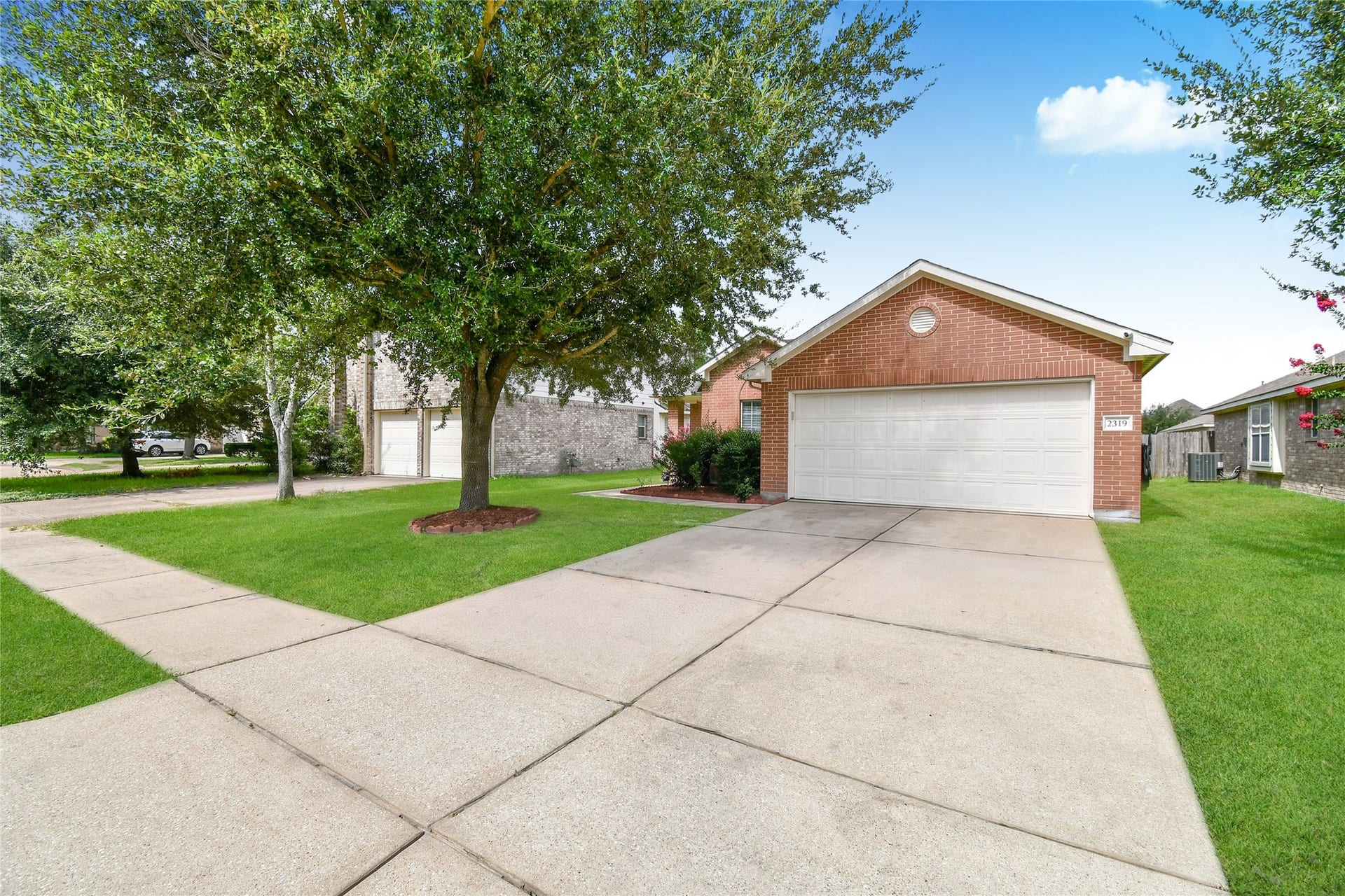 2319 Blue Reef Drive, Katy, TX 77449 Charming brick exterior with a mature shade tree, manicured lawn, and wide driveway leading to the two car garage.
