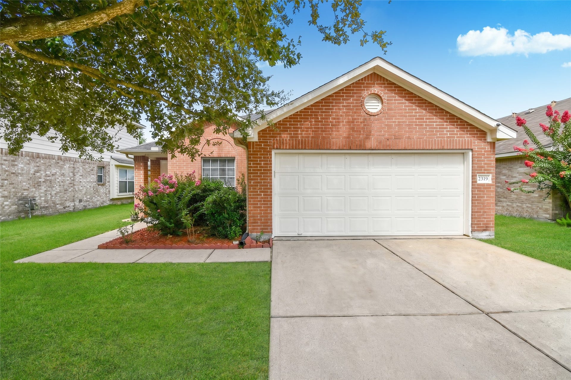 2319 Blue Reef Drive, Katy, TX 77449 Inviting front entrance featuring classic brick detailing, an arched window, and well maintained landscaping.