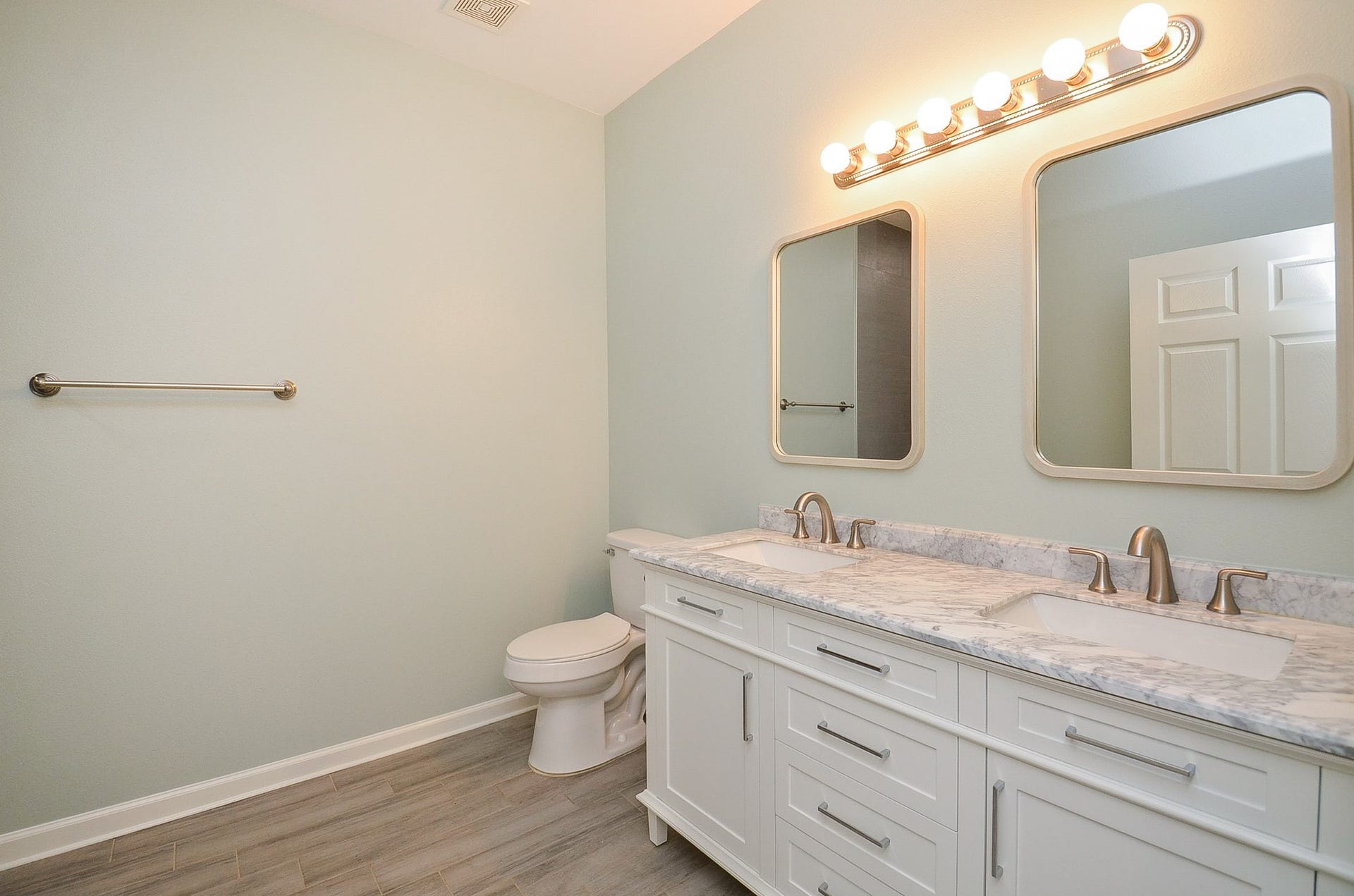 The sublime white/pastel toned primary ensuite bath offers dual sinks/vanity and storage, with delicate lighting above.