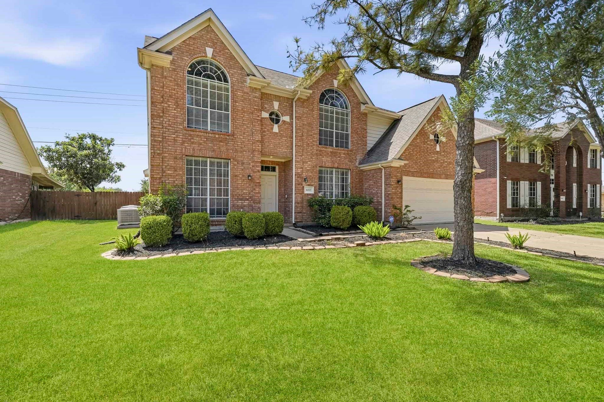 16527 Fondren Grove Drive, Missouri City, TX 77489 Charming two-story brick home with elegant arched windows, manicured landscaping, and a spacious two-car garage nestled in a serene neighborhood.