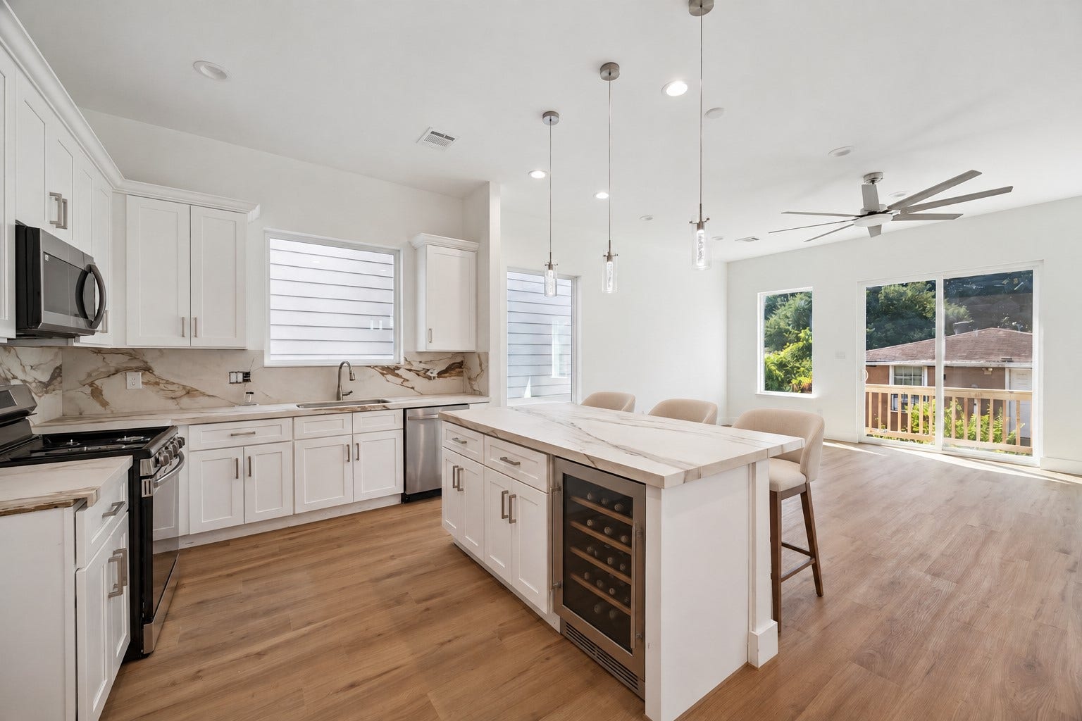 5310 Salina Street, Houston, TX 77026 The bright kitchen opens effortlessly into the main living area, creating a contemporary space designed for both everyday living and entertaining. White cabinetry, stainless steel appliances, marble-look countertops and backsplash, pendant lighting, and warm wood-look flooring create a clean, cohesive aesthetic. A generous island provides additional prep space while large windows and sliding glass doors bring in abundant natural light.