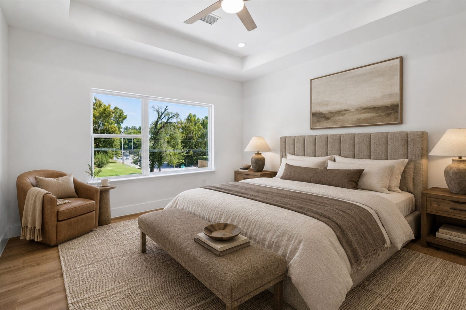 5310 Salina Street, Houston, TX 77026 The spacious bedroom offers a bright and peaceful retreat with warm wood-look flooring, crisp neutral walls, and a large window overlooking mature greenery. A tray-style ceiling adds architectural interest, while recessed lighting and a contemporary ceiling fan enhance comfort. The generous dimensions allow room for a complete bedroom suite, additional seating, or a work-from-home area. This photo has been virtually staged for visual reference.