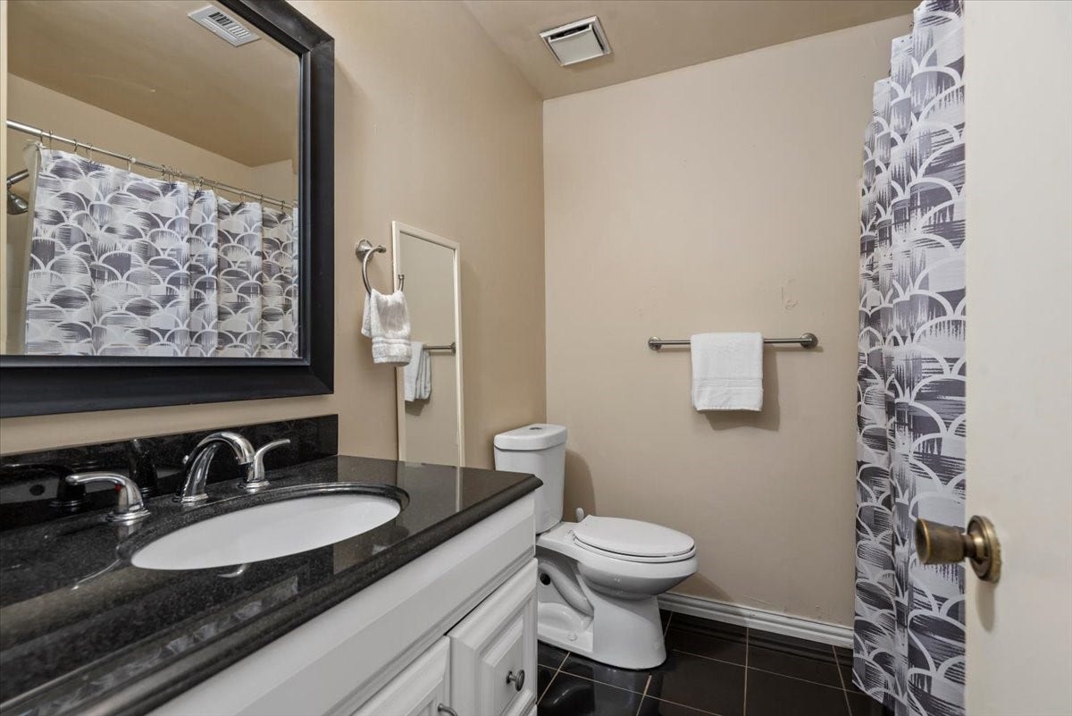 9522 Wellsworth Drive, Houston, TX 77083 Clean, updated bath with sleek dark countertop and tub-shower combo