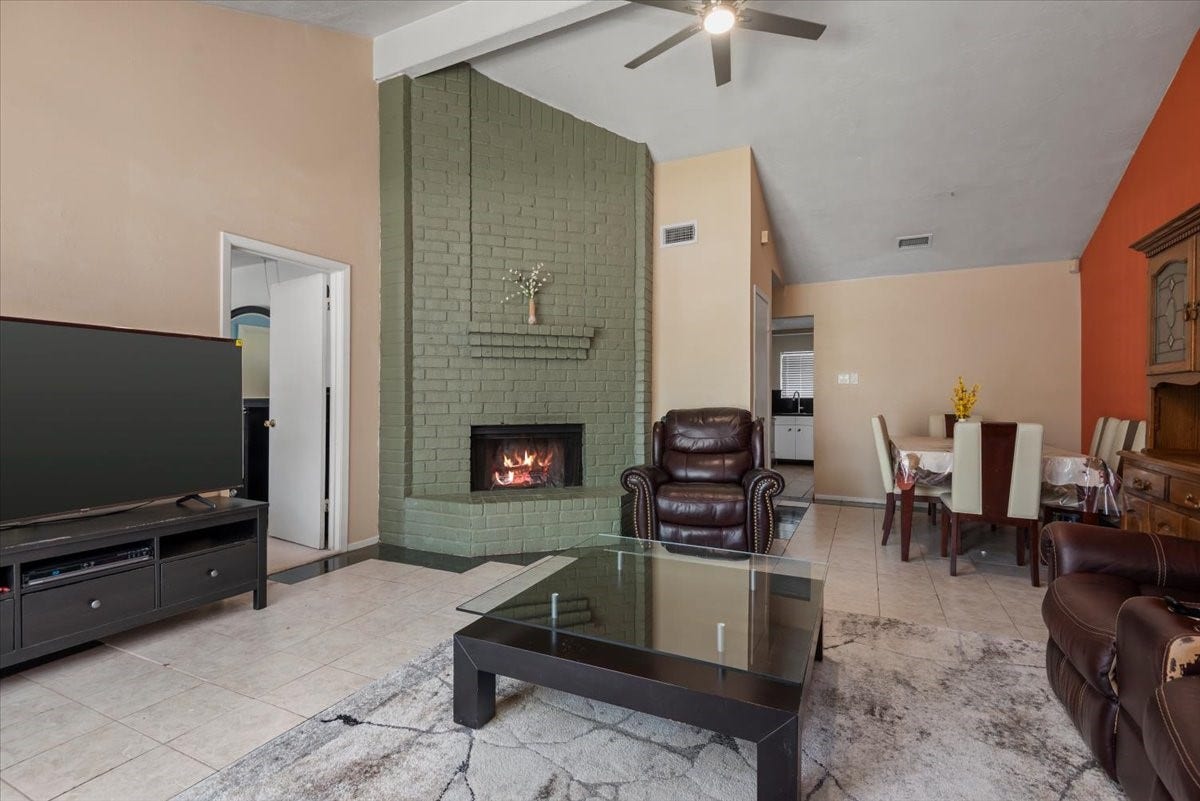 9522 Wellsworth Drive, Houston, TX 77083 Open-concept living and dining area in duplex unit with ceiling fan and fireplace
