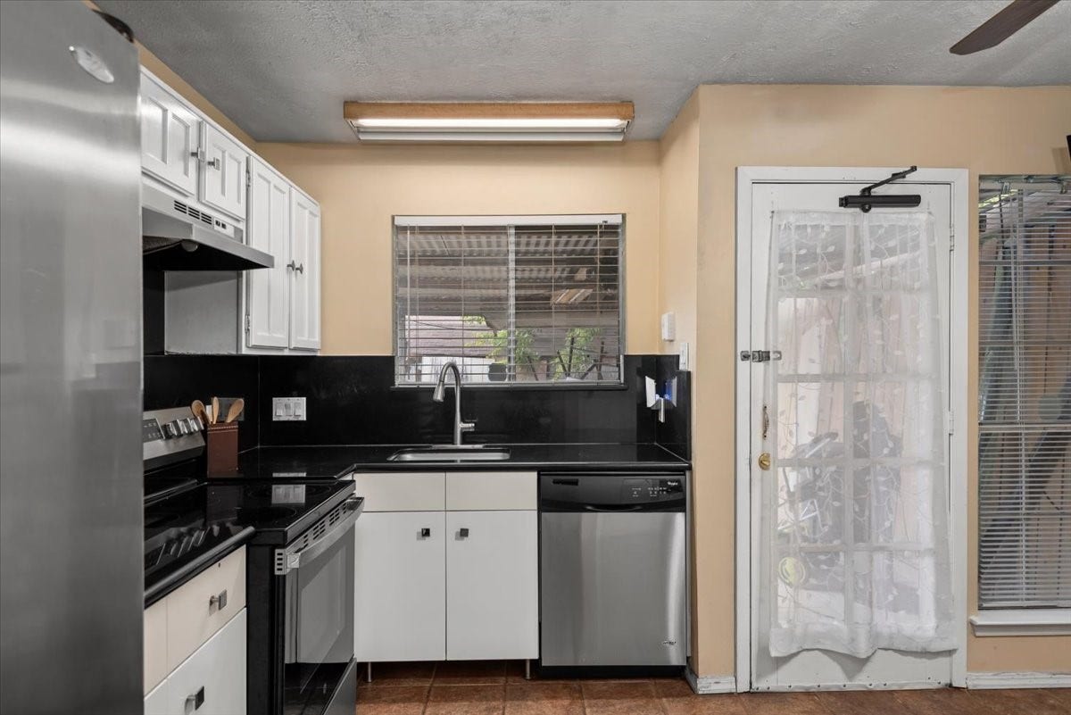 9522 Wellsworth Drive, Houston, TX 77083 Kitchen with white cabinetry, dark countertops, stainless steel appliances, and window over the sink