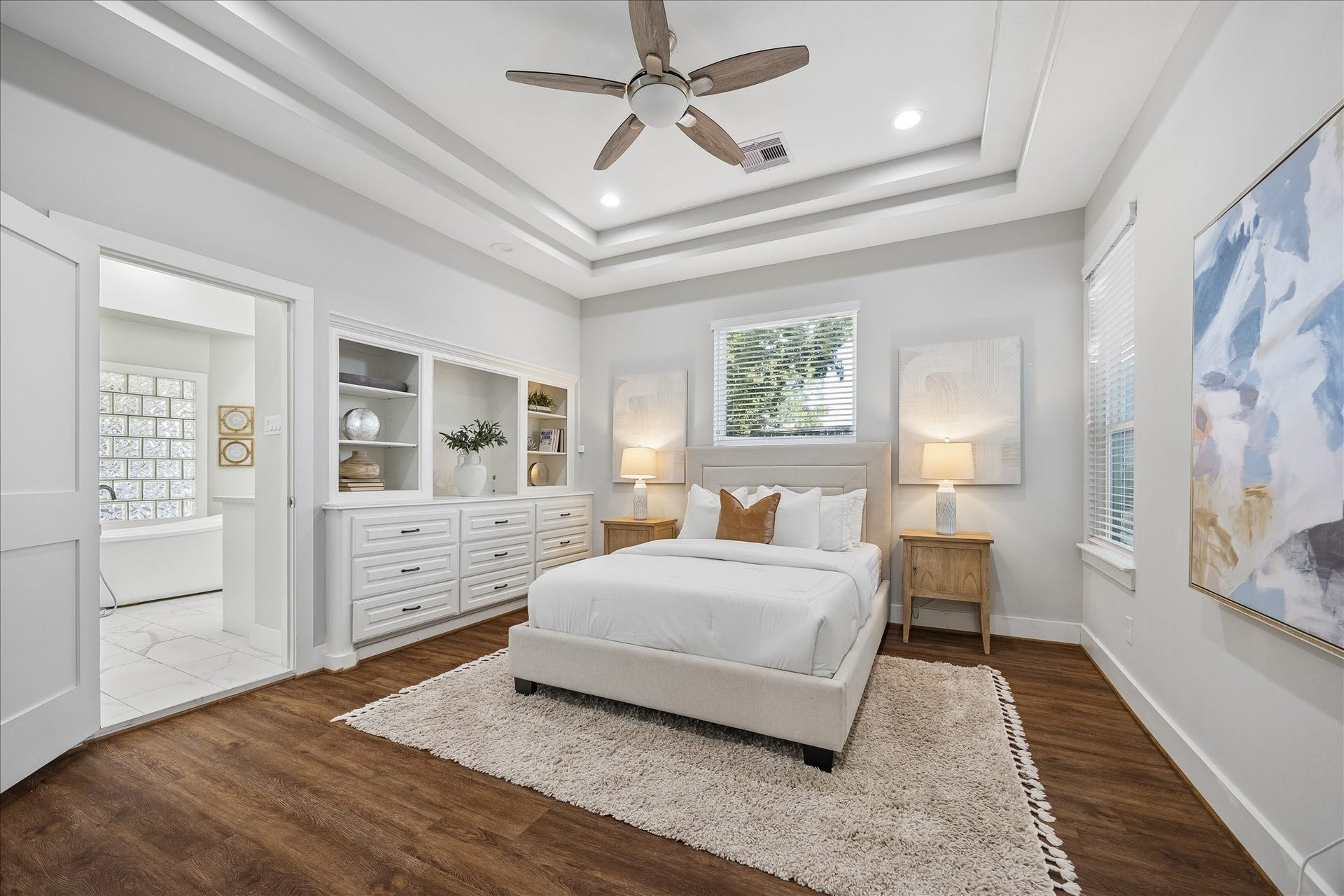 702 W 41st Street, Houston, TX 77018 Your own private retreat awaits. This luxurious primary suite offers a beautiful triple tray ceiling, custom built-ins and updated luxury vinyl tile flooring. With extensive closet space and a spa-like ensuite just steps away, you'll love having a peaceful place to escape, recharge and enjoy a little well-deserved downtime.