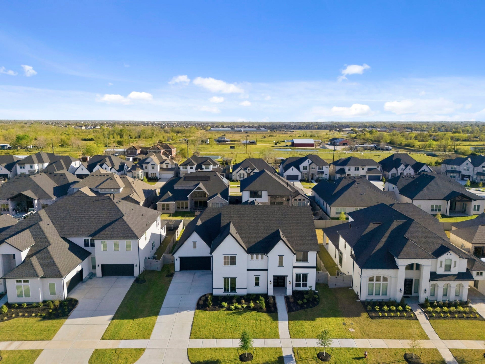Modern suburban neighborhood with spacious, stylish homes featuring well-maintained lawns. The area is open and airy, offering a sense of community with easy access to green spaces.